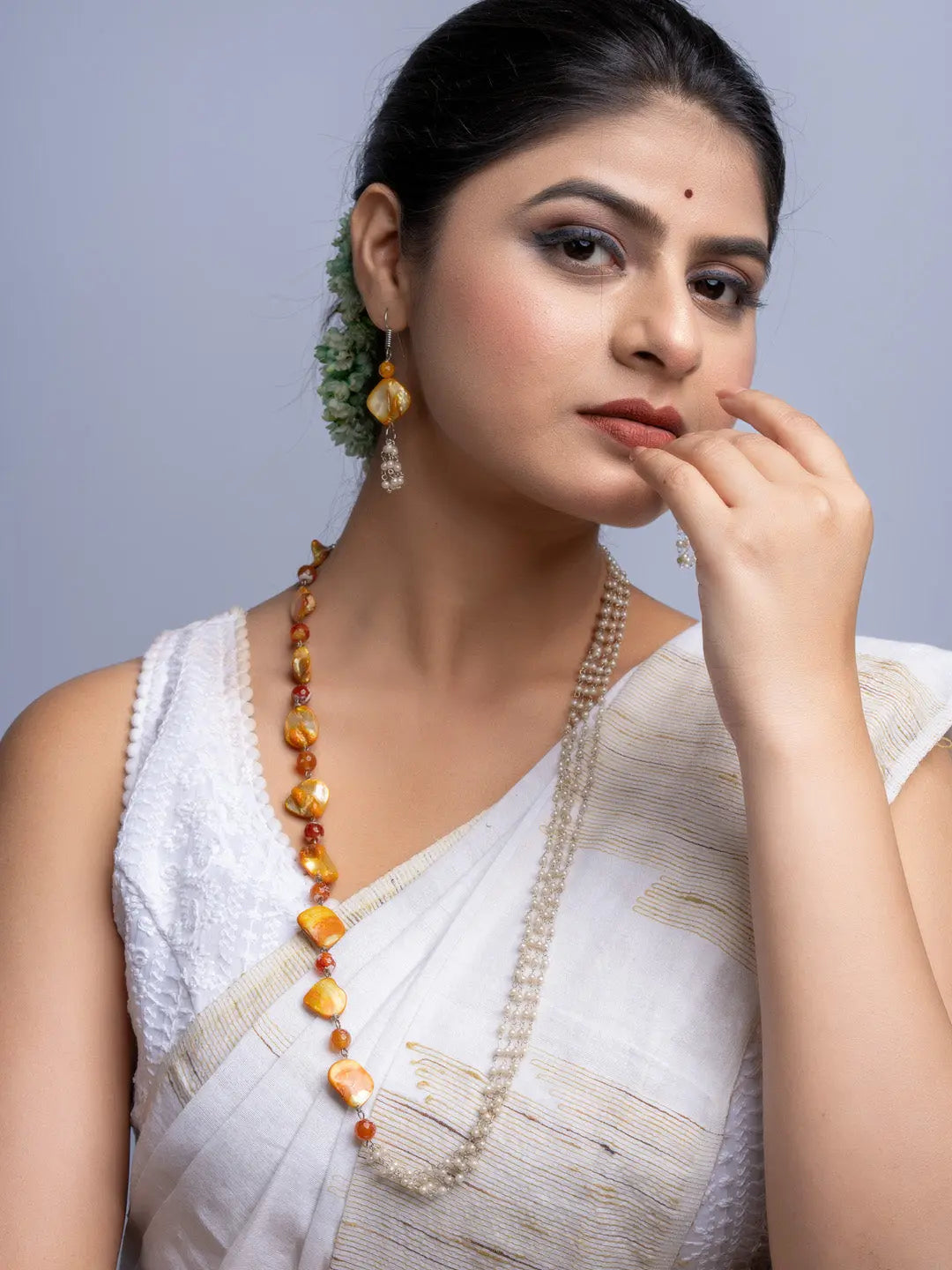 Woman wearing handmade mother of pearl necklace set with white saree and matching earrings