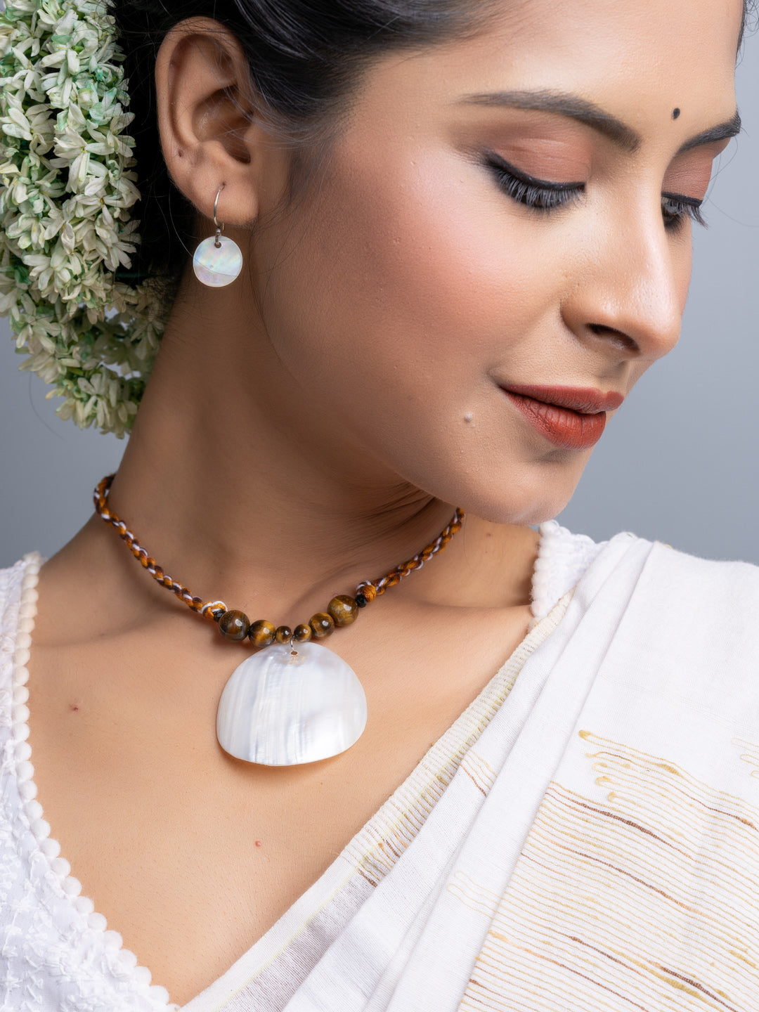 Woman wearing a handmade mother of pearl necklace set with matching earrings and floral hair accessory