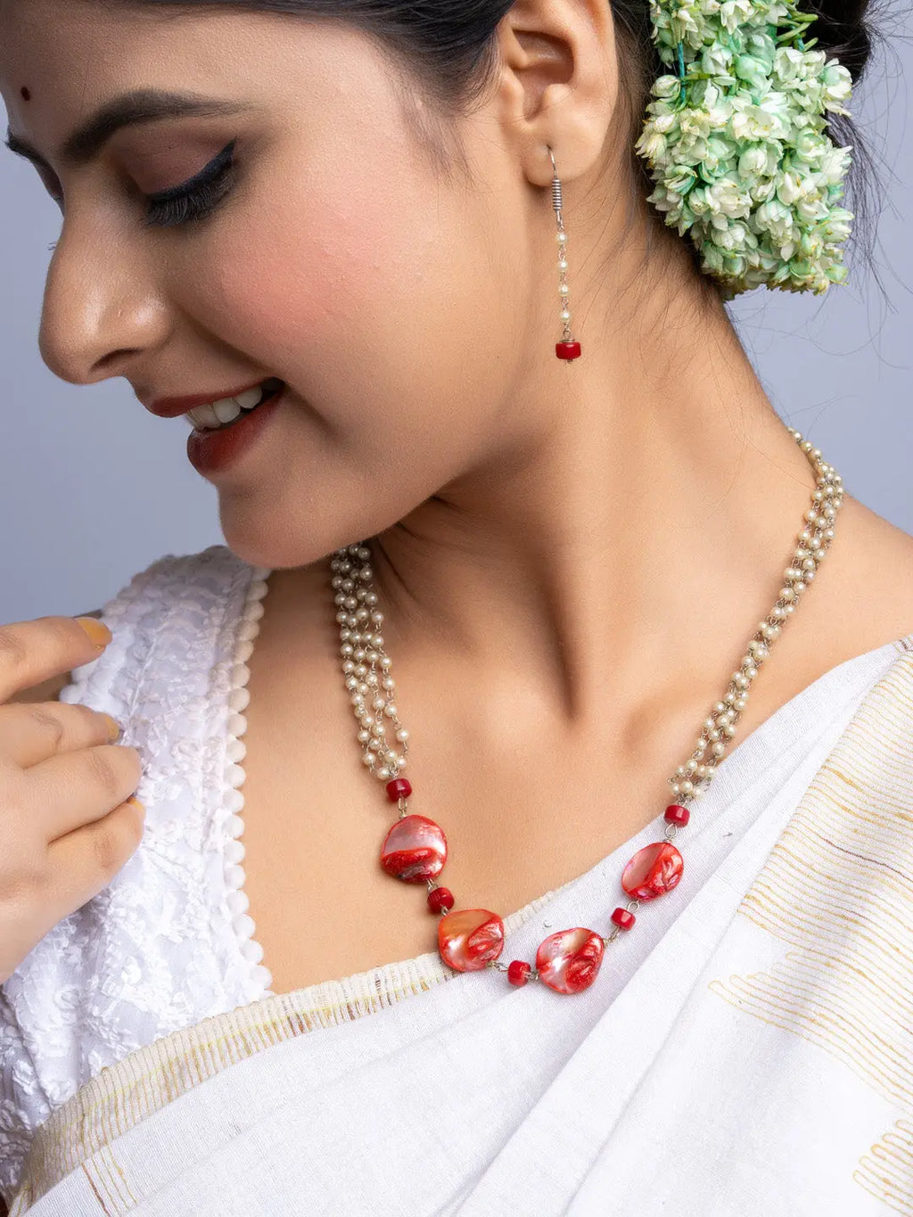 Close-up of woman wearing handmade mother of pearl necklace set with red beads and white pearls