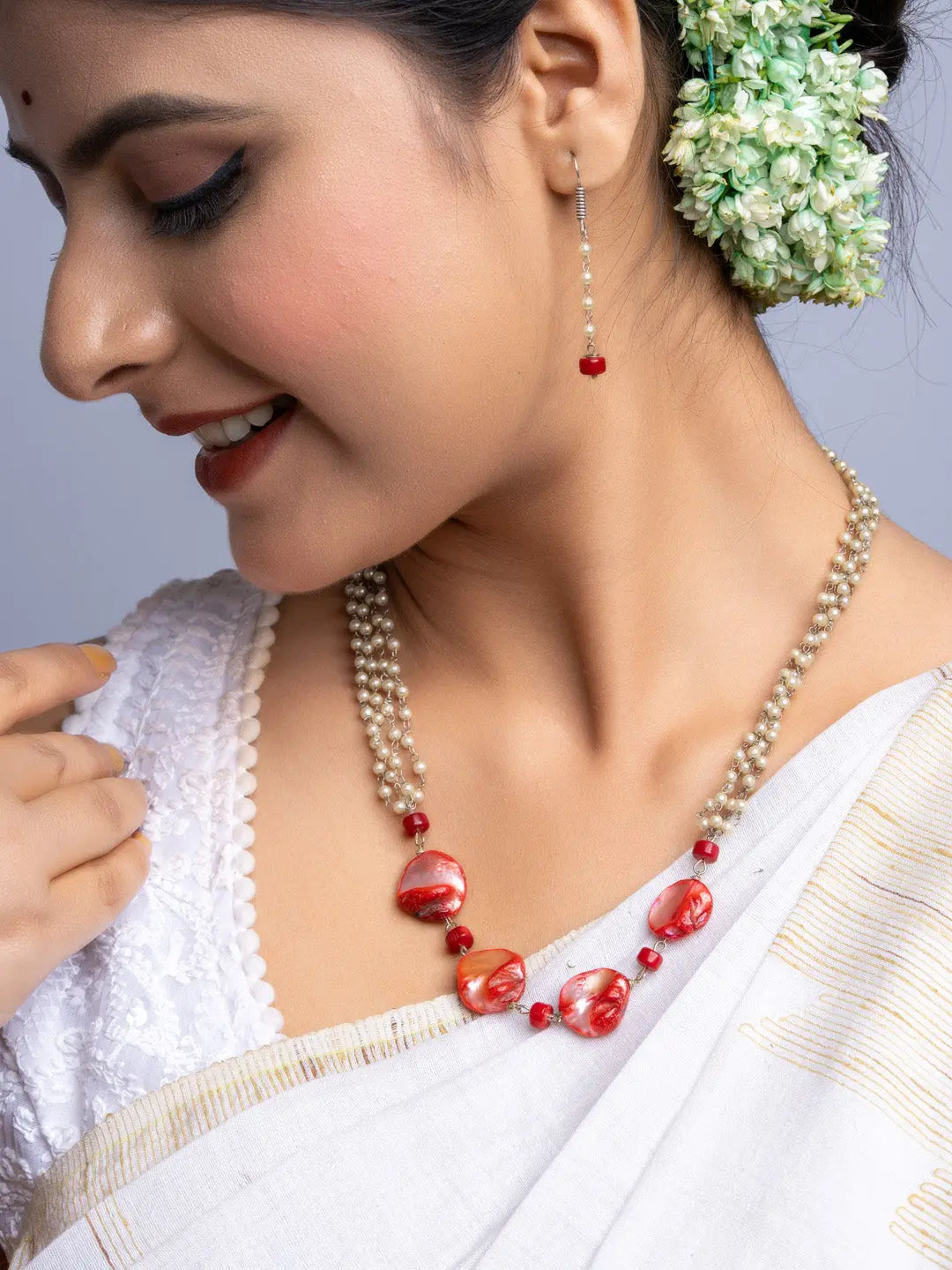 Close-up of woman wearing handmade mother of pearl necklace set with red beads and white pearls