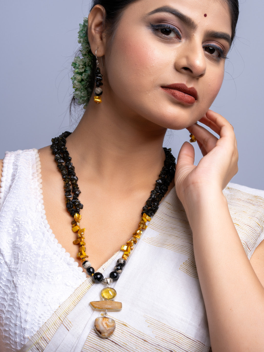 Handmade Mother of Pearl Necklace Set featuring black and amber beads worn by woman in white dress