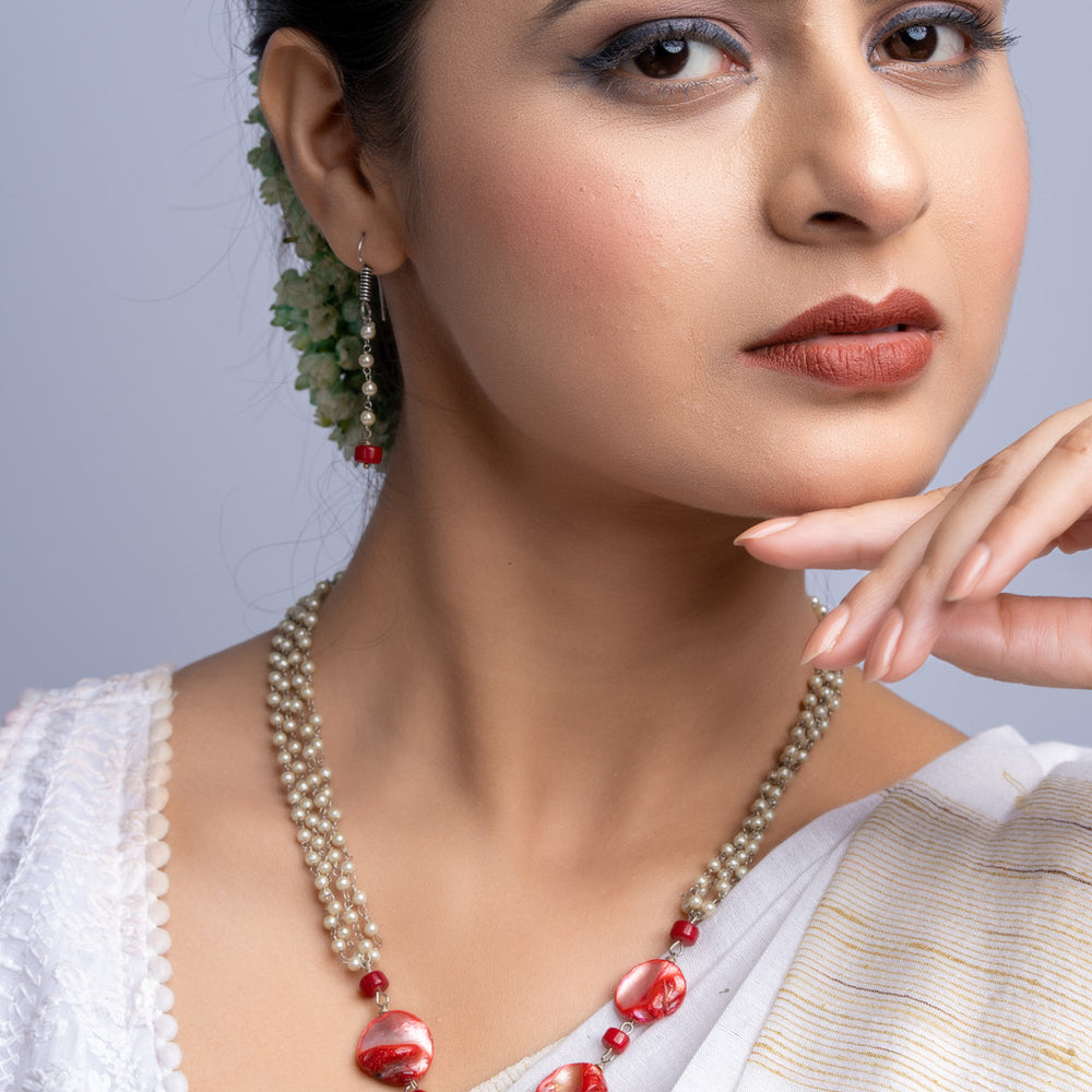 Elegant mother of pearl necklace set featuring red and white beads worn by woman in traditional attire
