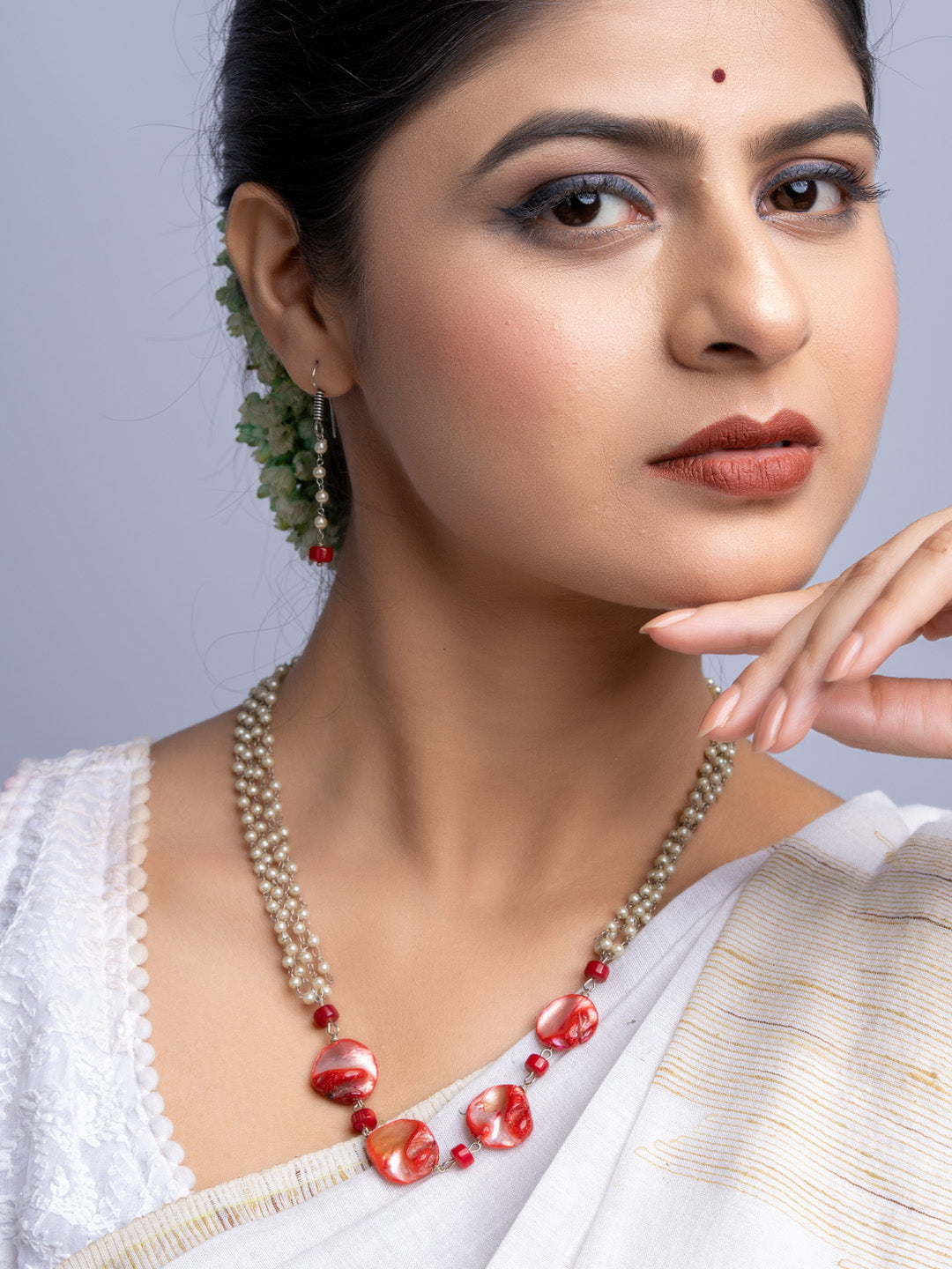 Elegant mother of pearl necklace set featuring red and white beads worn by woman in traditional attire