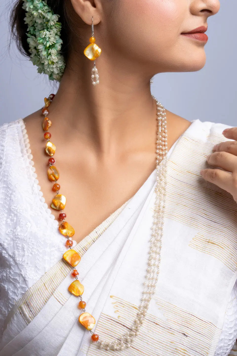 Elegant mother of pearl necklace set worn with traditional white saree and floral hair accessory