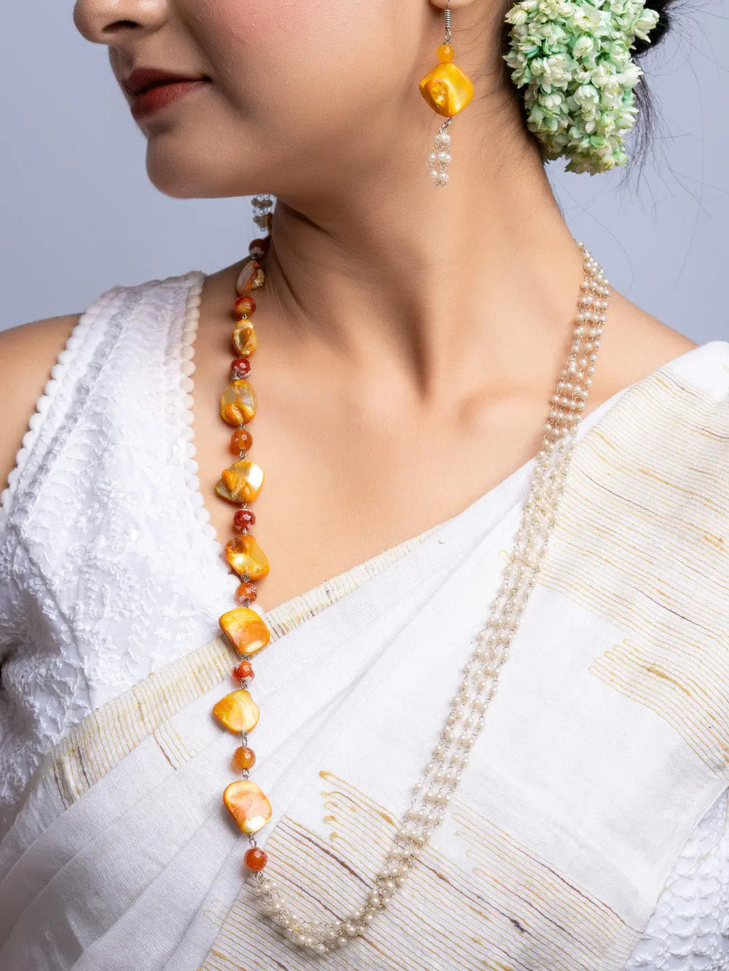Handmade mother of pearl necklace set in yellow and white worn with traditional white sari and floral hair accessory