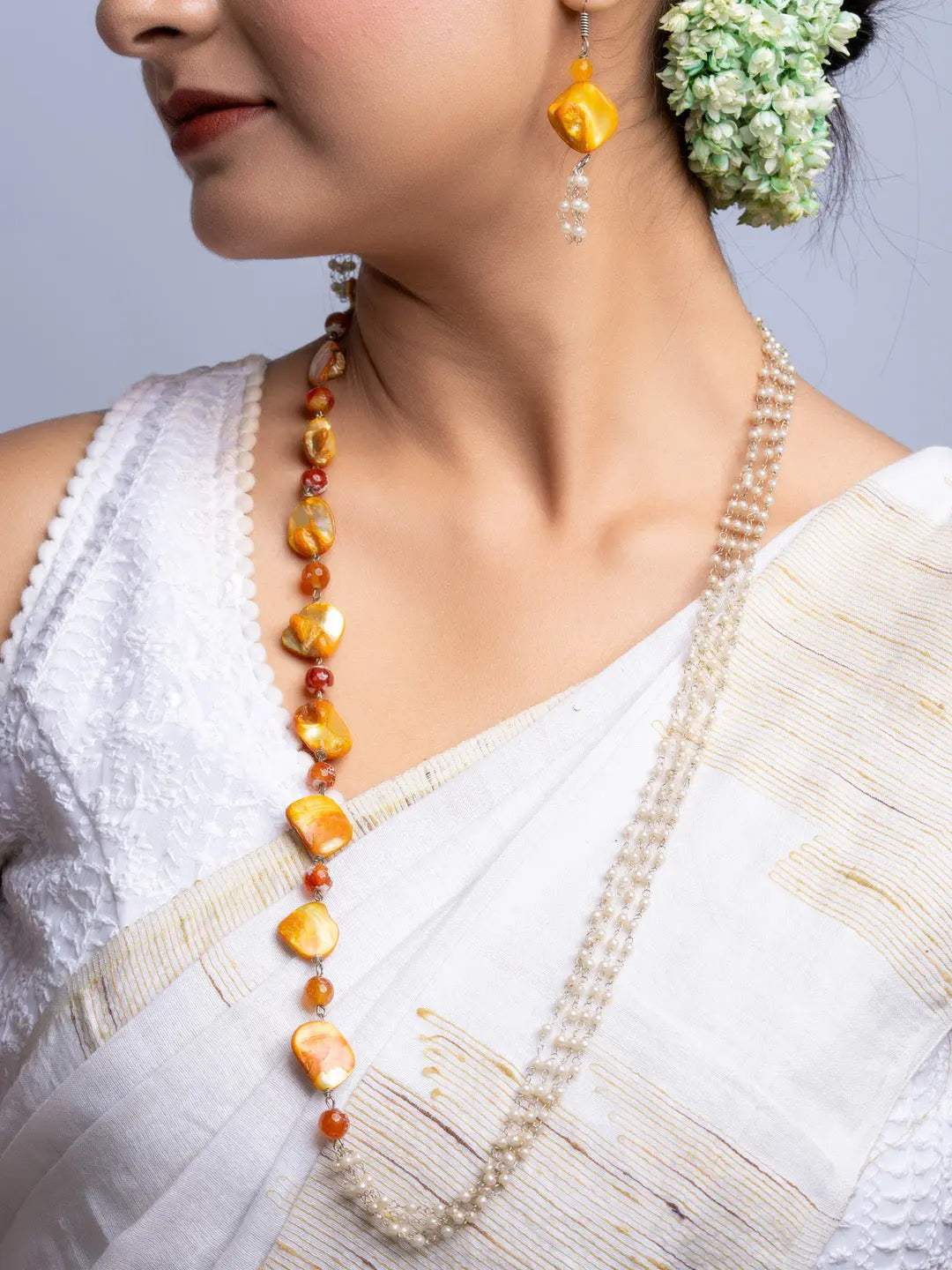Handmade mother of pearl necklace set in yellow and white worn with traditional white sari and floral hair accessory