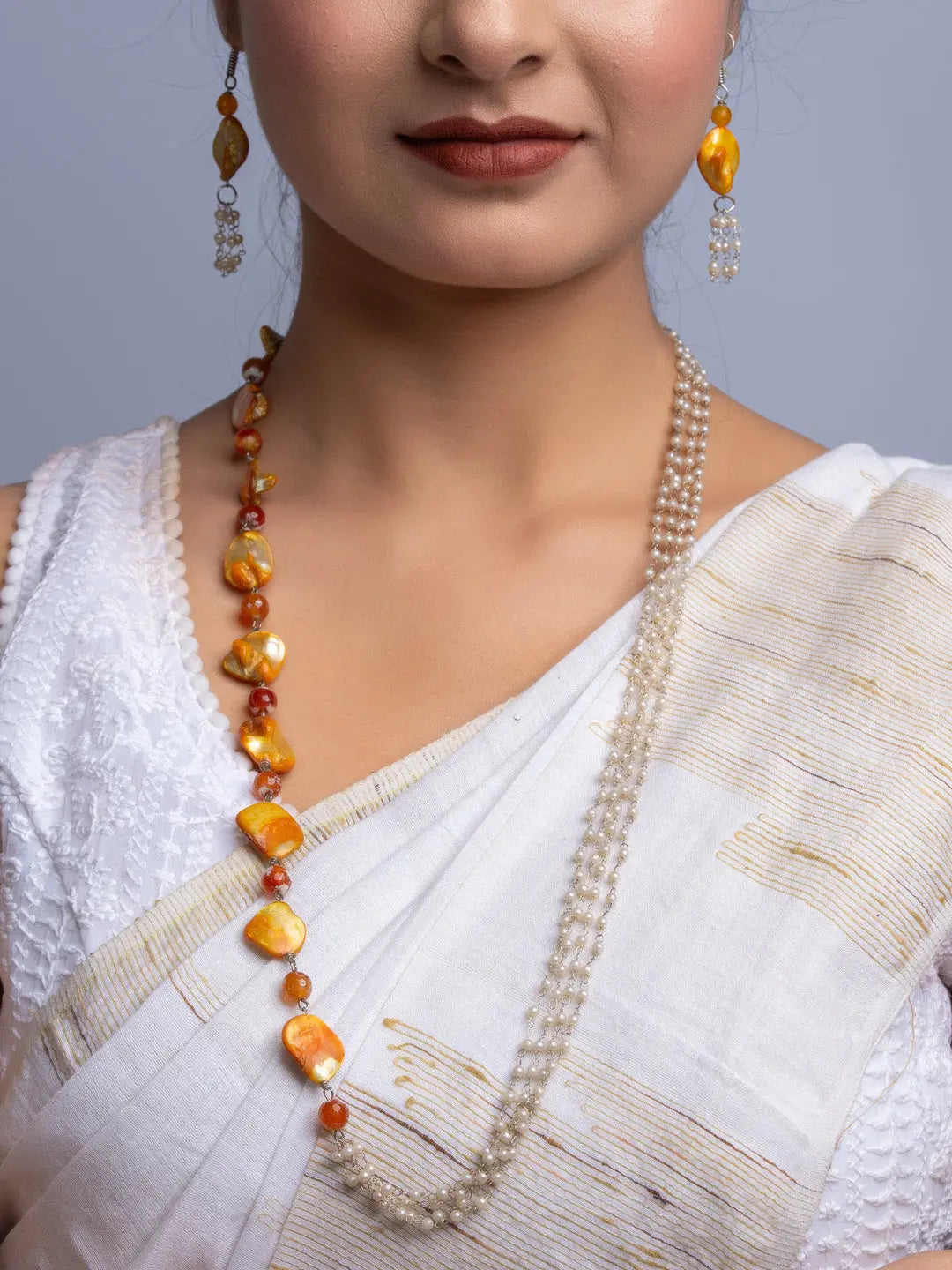 Woman wearing a handmade mother of pearl necklace set with orange and white beads and matching earrings