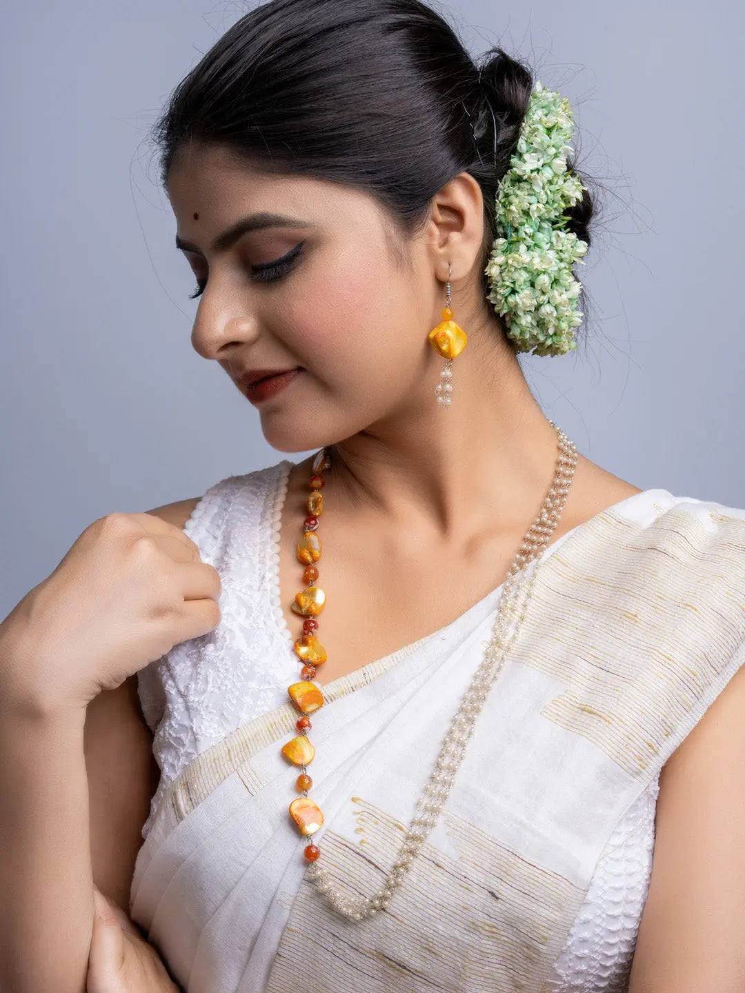Woman wearing a handmade mother of pearl necklace set with orange and white beads in traditional attire