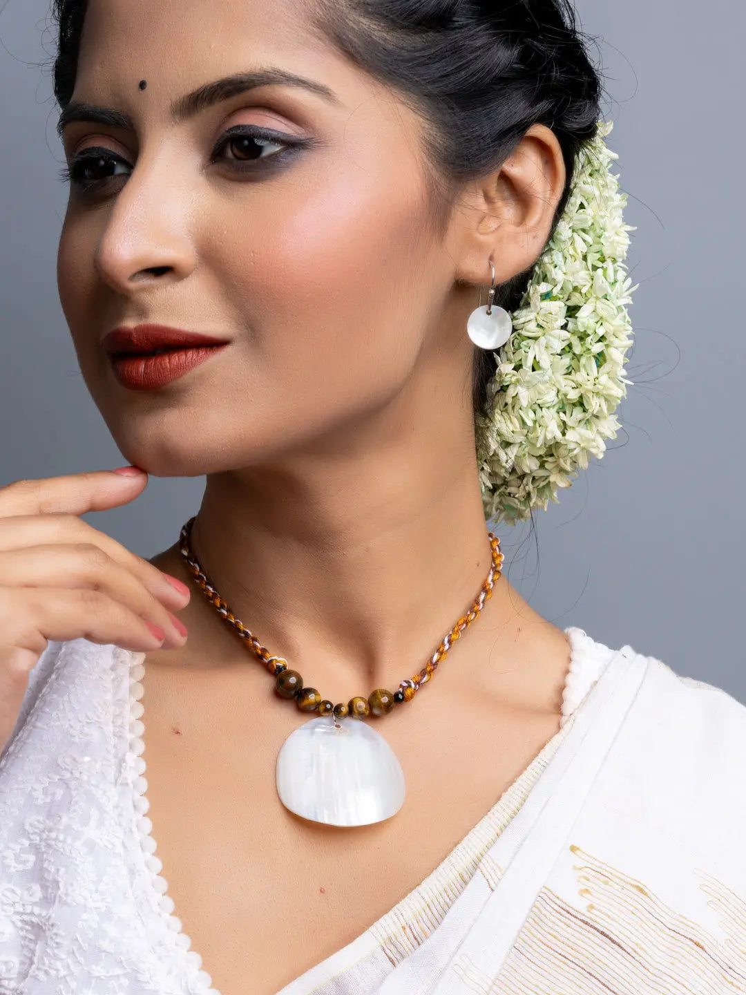 Handmade mother of pearl necklace set with large pendant and matching earrings worn by woman