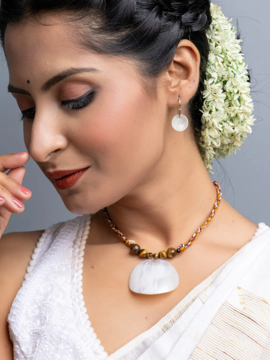 Handmade mother of pearl necklace set featuring a white shell pendant and matching earrings worn by a woman