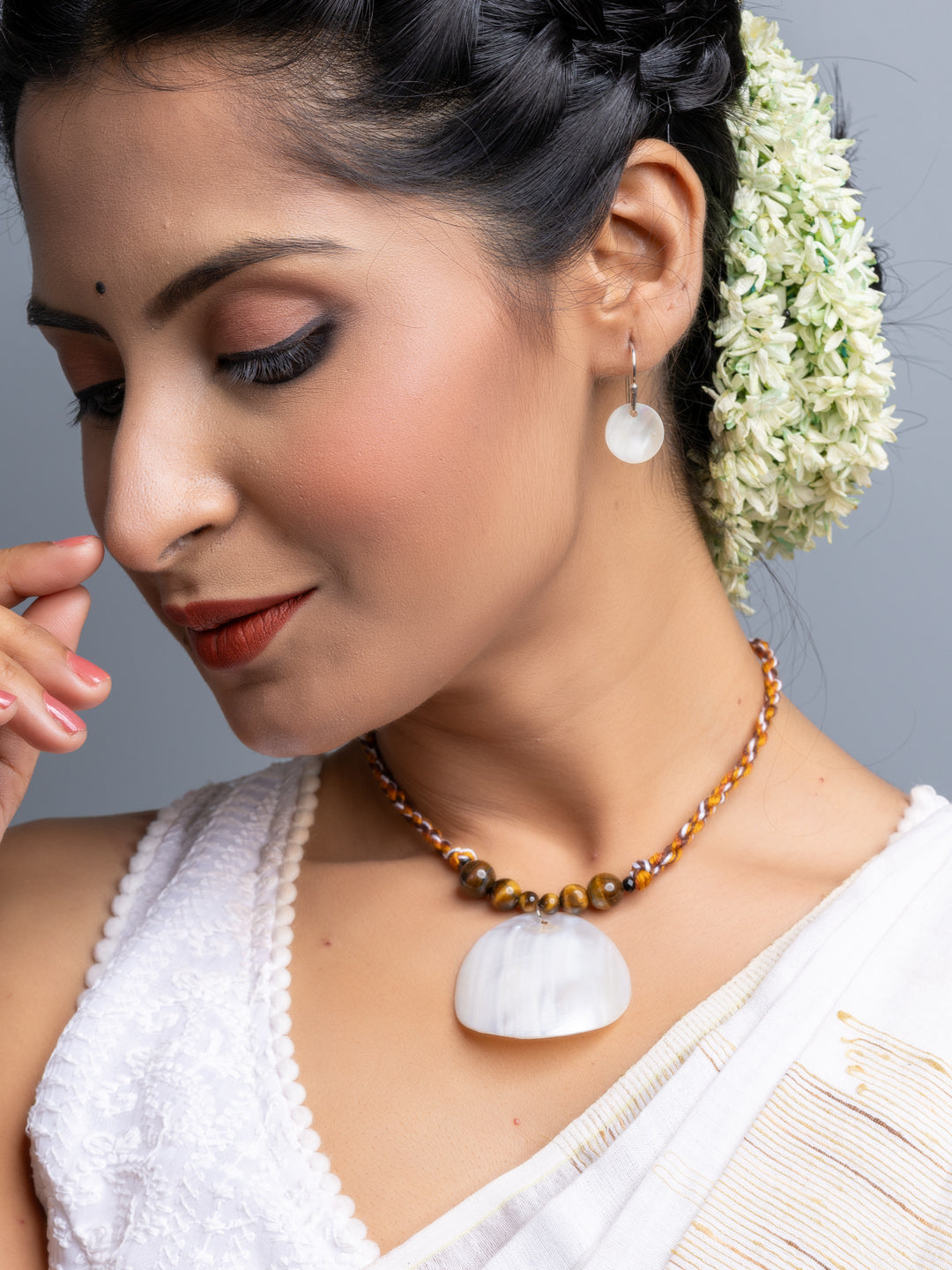 Handmade mother of pearl necklace set featuring a white shell pendant and matching earrings worn by a woman