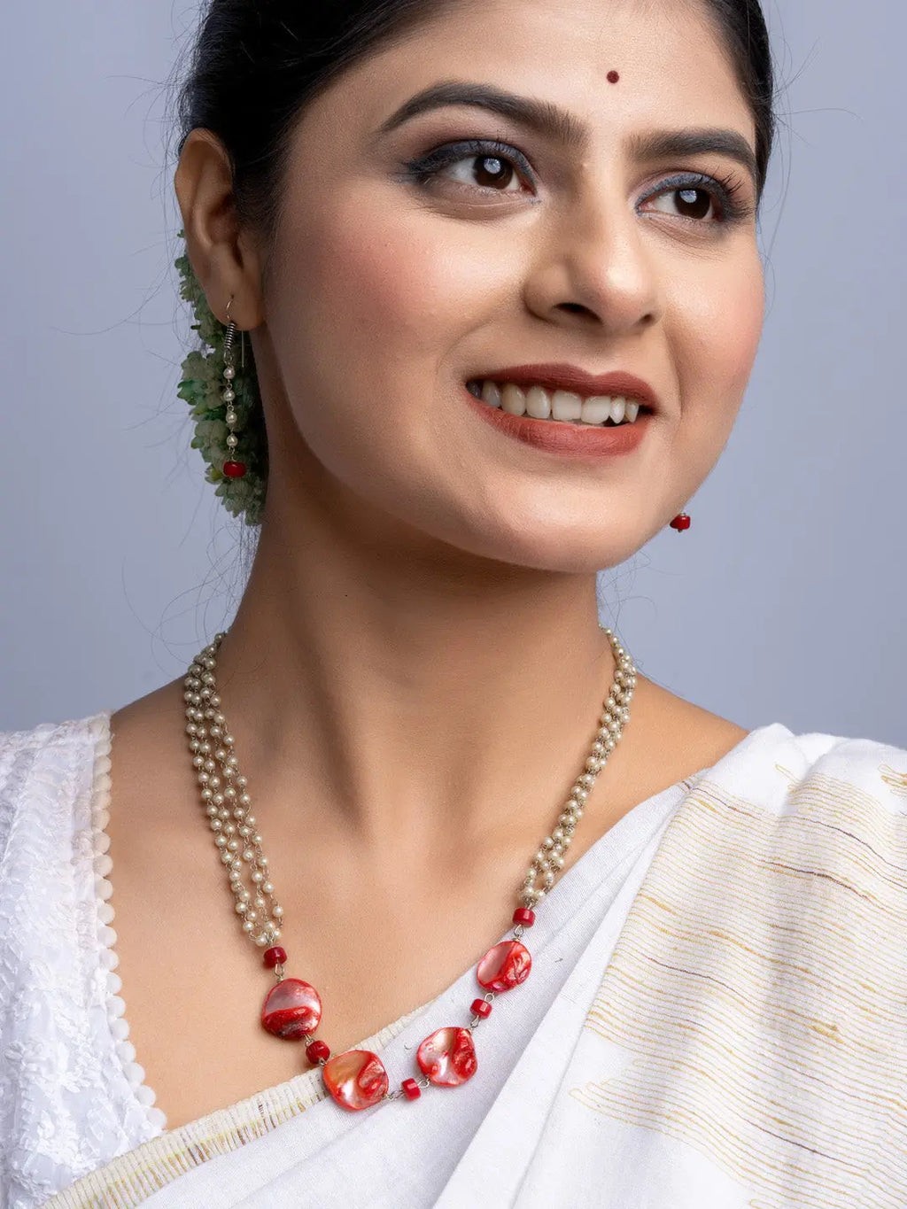 Woman wearing handmade mother of pearl necklace set with red beads and white traditional attire