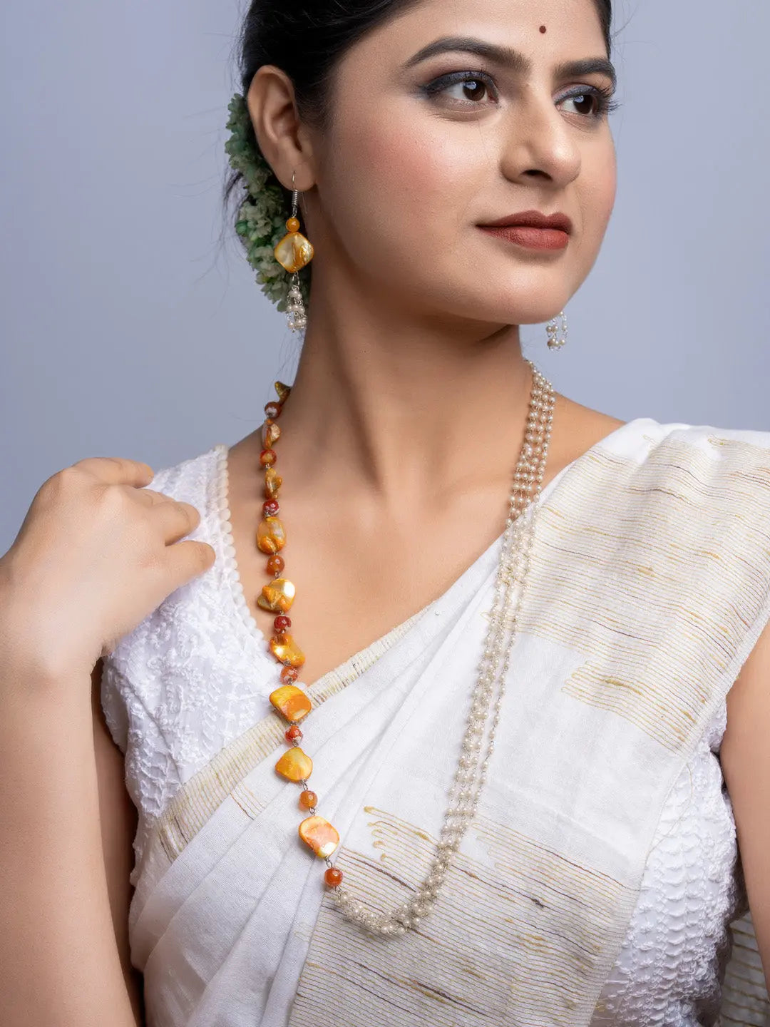 Elegant mother of pearl necklace set worn by woman in white saree featuring handmade jewelry
