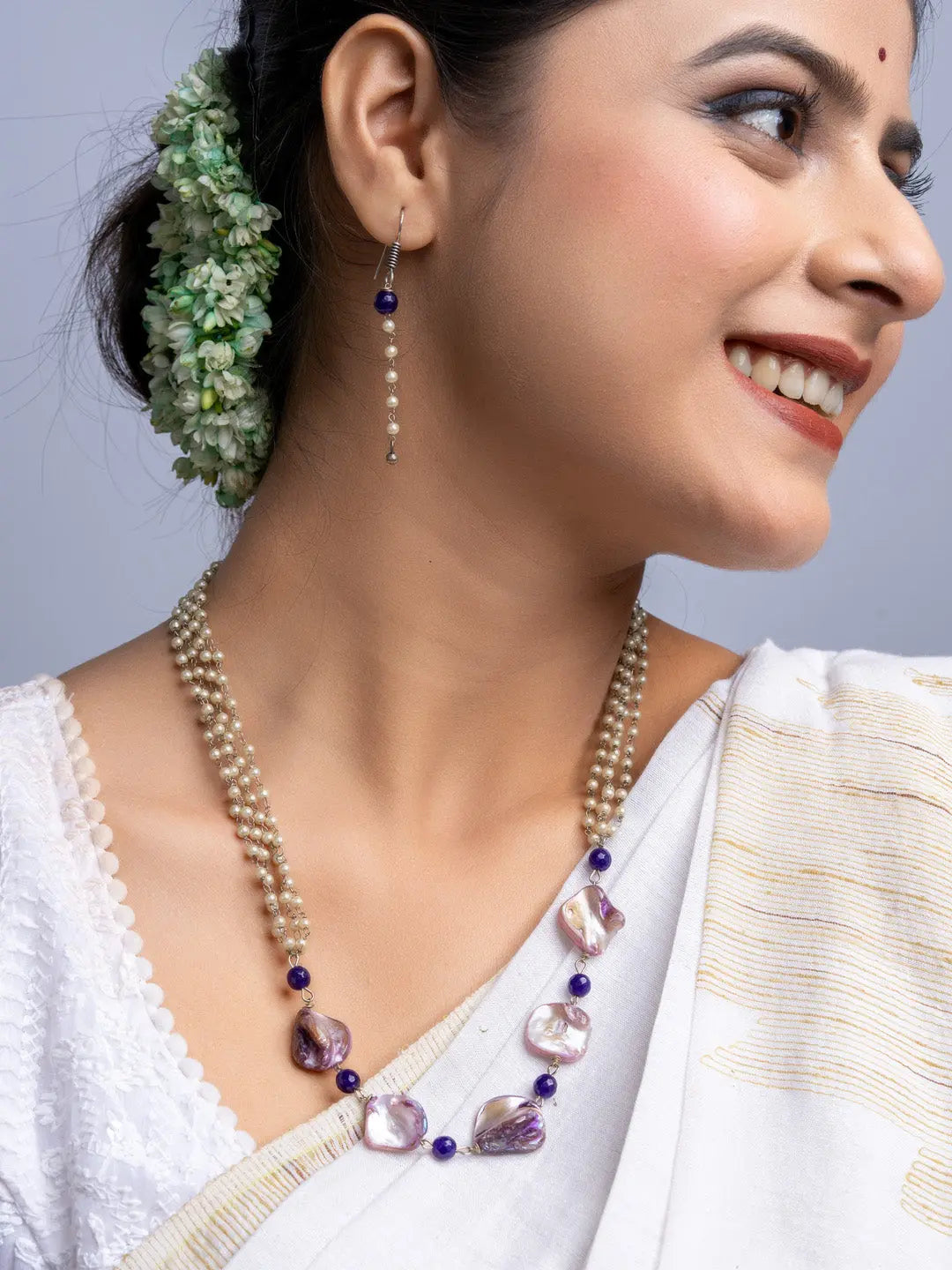 Elegant mother of pearl necklace set with purple beads worn by a woman in traditional attire