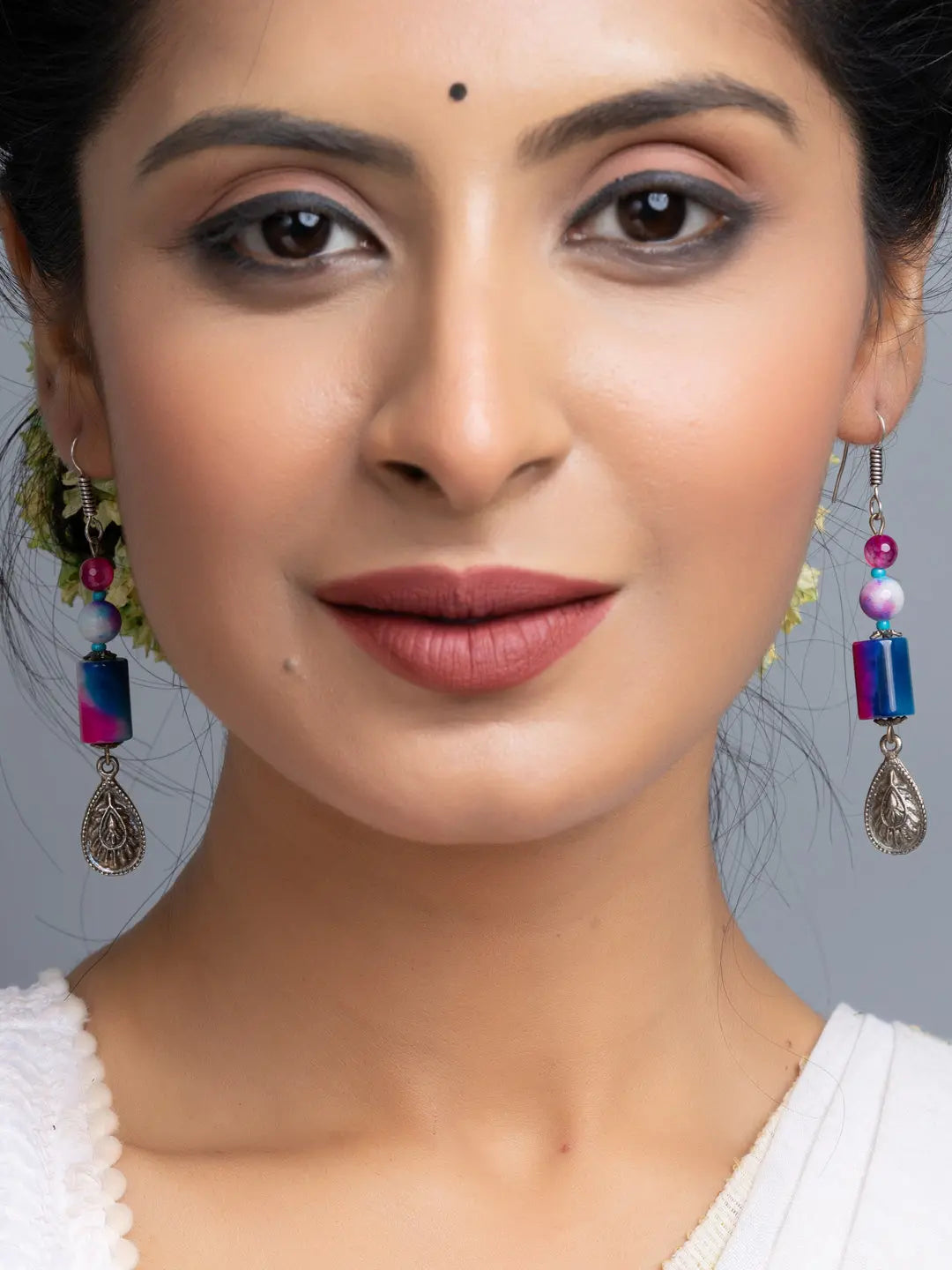 Close-up of woman wearing handmade onyx earrings with colorful beads and silver charms