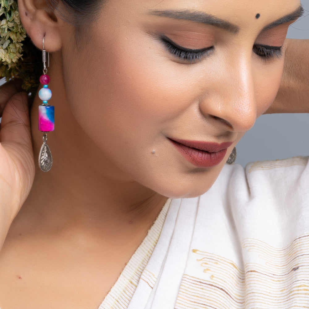 Close-up of woman wearing colorful handmade onyx earrings with beads and silver charm