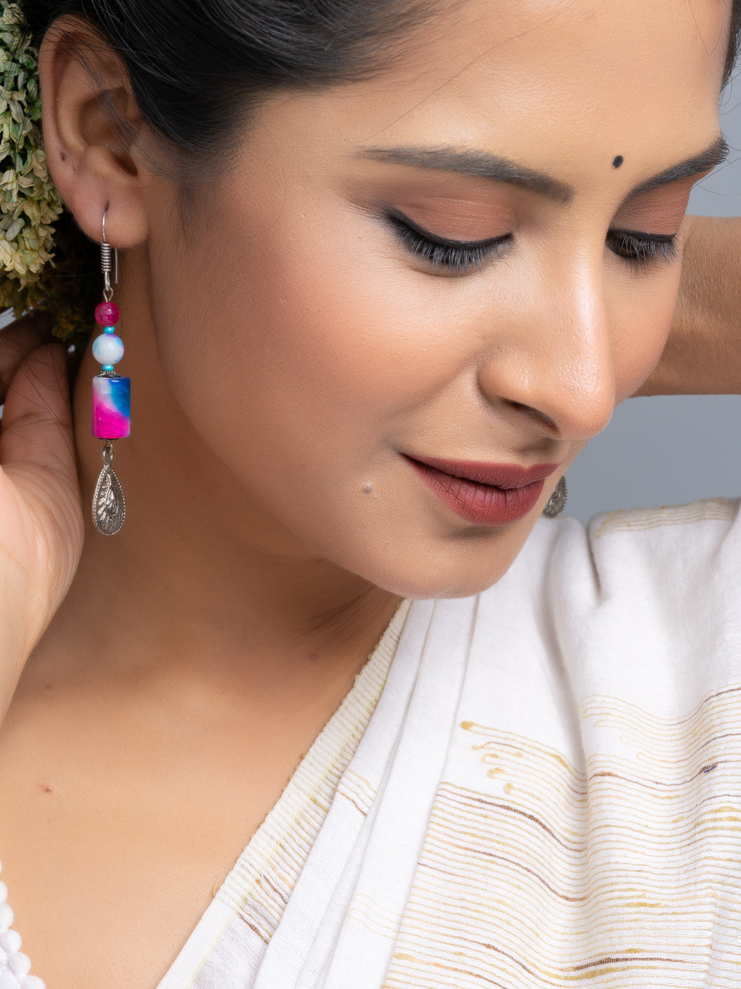 Close-up of woman wearing colorful handmade onyx earrings with beads and silver charm