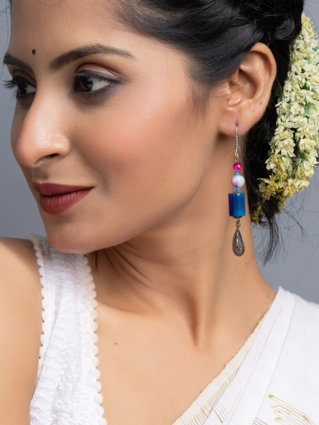 Handmade onyx earrings featuring blue beads and silver drop detail worn by woman with traditional attire