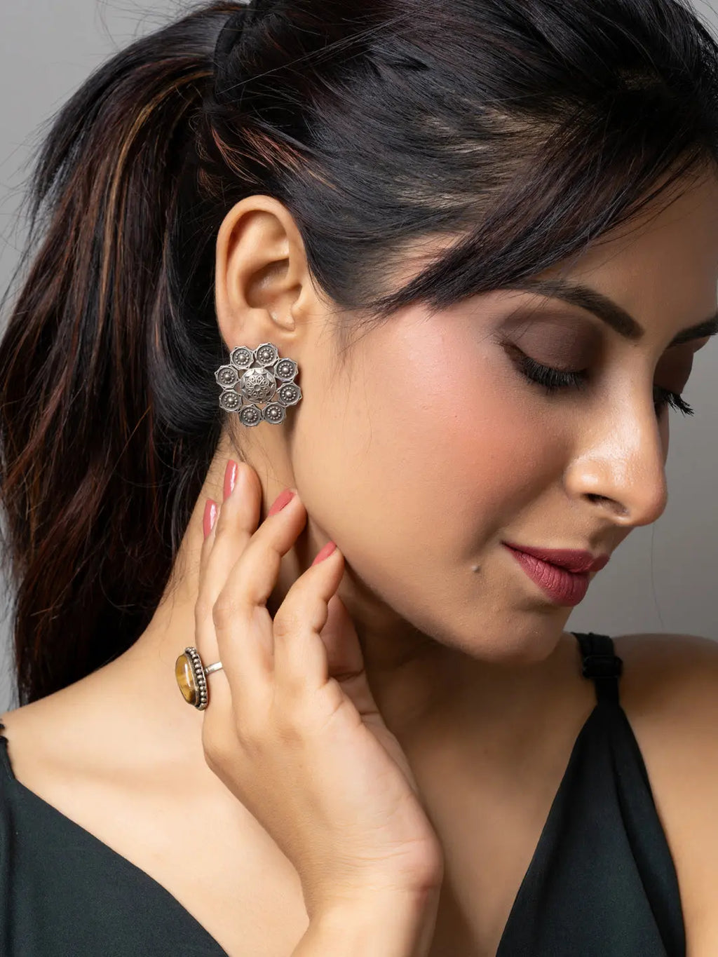 Stylish oxidised earrings in intricate circular design worn by woman with dark hair and makeup