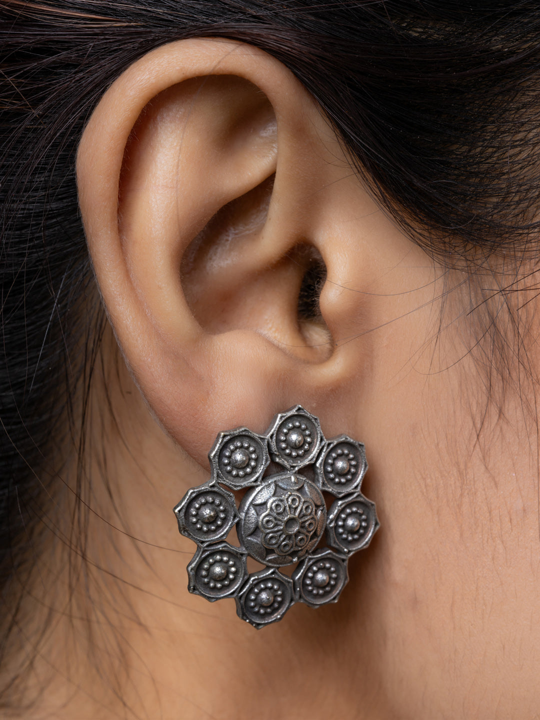 Close-up of a person wearing oxidised earrings from LOOK AND ADORN featuring floral design in oxidised silver