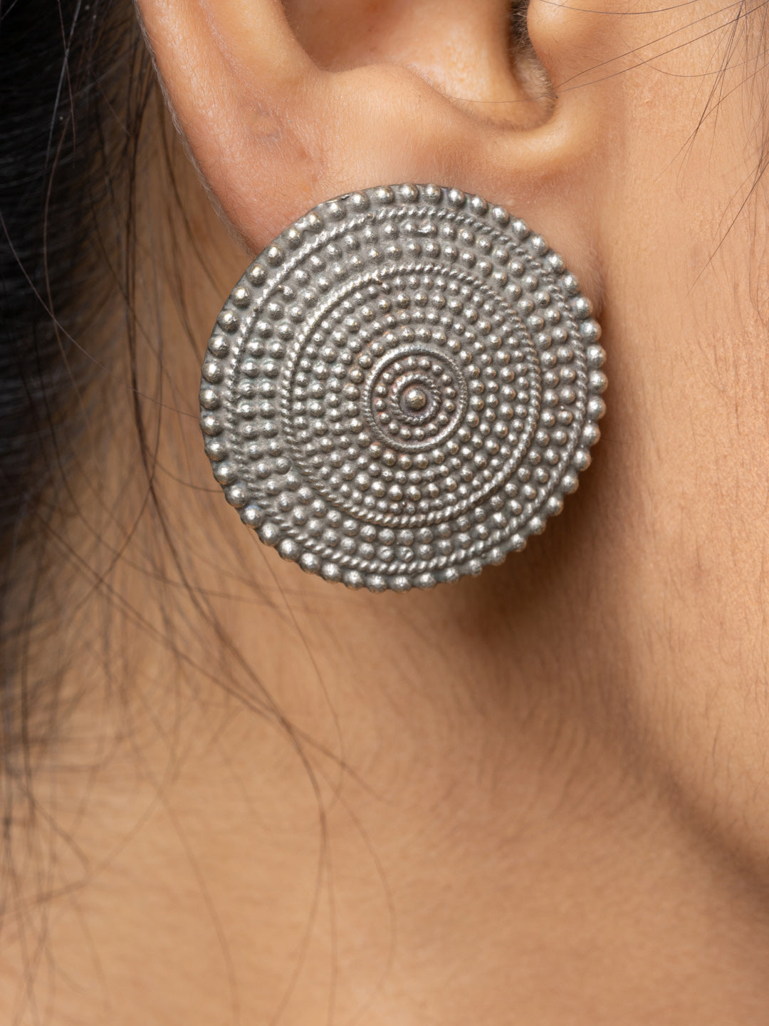 Close-up of oxidised earrings with circular detailed bead design worn on ear
