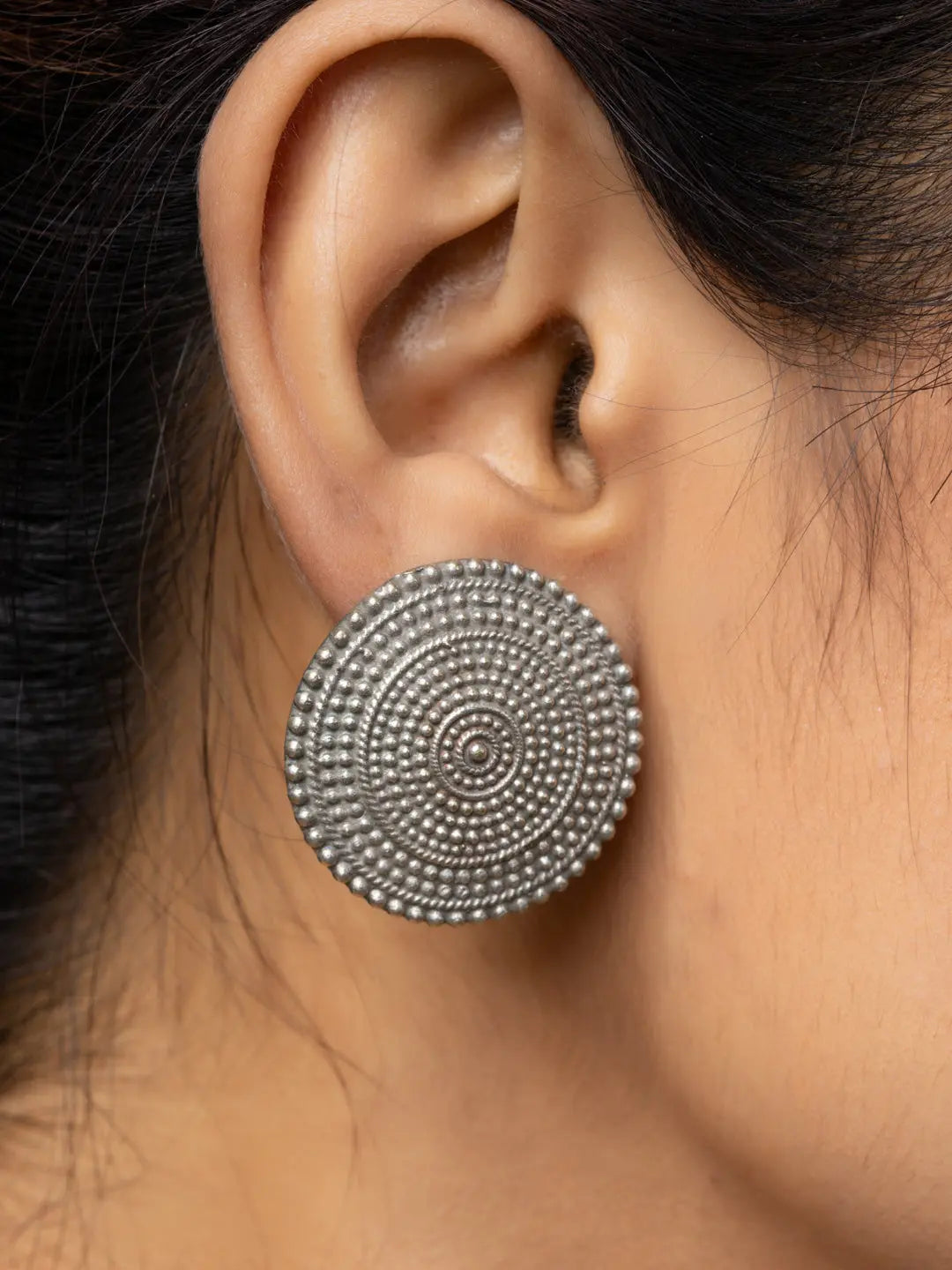 Close-up of a woman wearing circular oxidised earrings with intricate bead detailing from LOOK AND ADORN