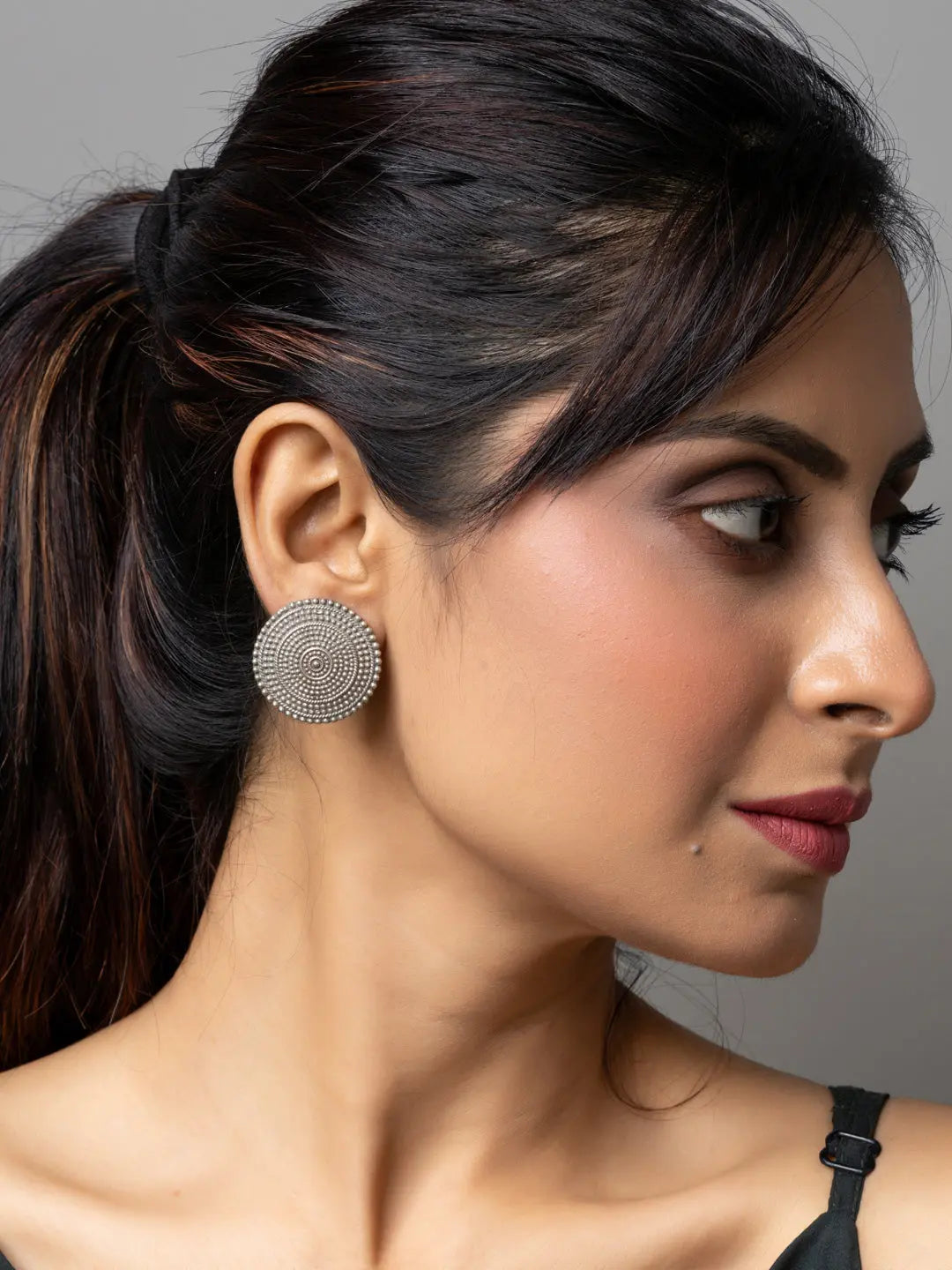 Woman wearing round oxidised earrings from LOOK AND ADORN with intricate circular design