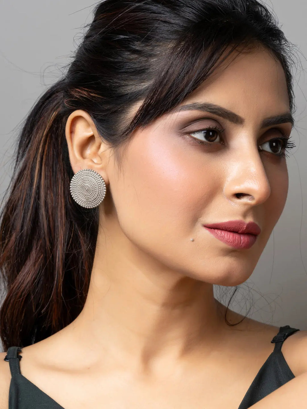Close-up of woman wearing round oxidised earrings with intricate design from LOOK AND ADORN