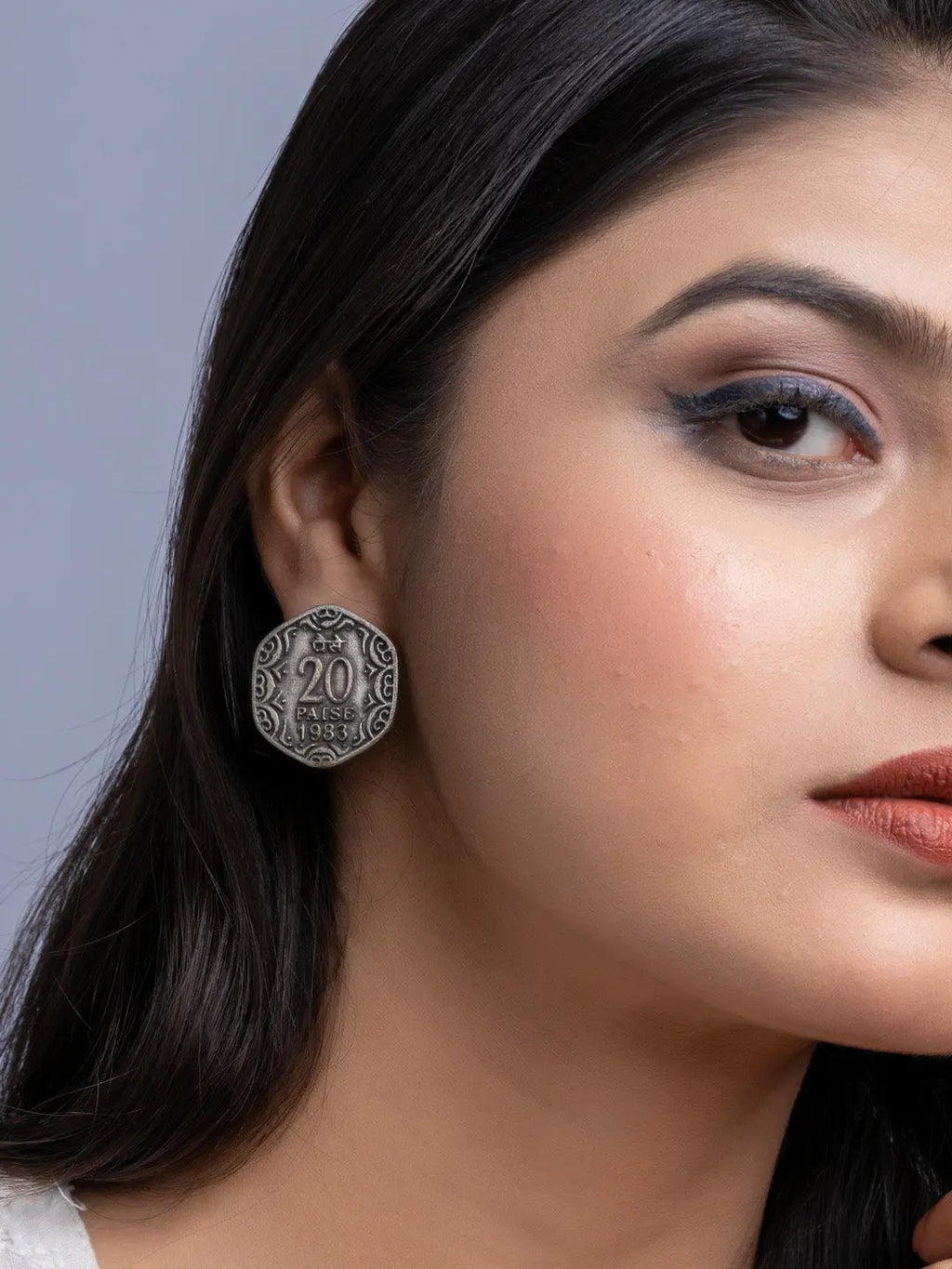 Close-up of oxidised silver earrings worn by a woman with long dark hair and makeup