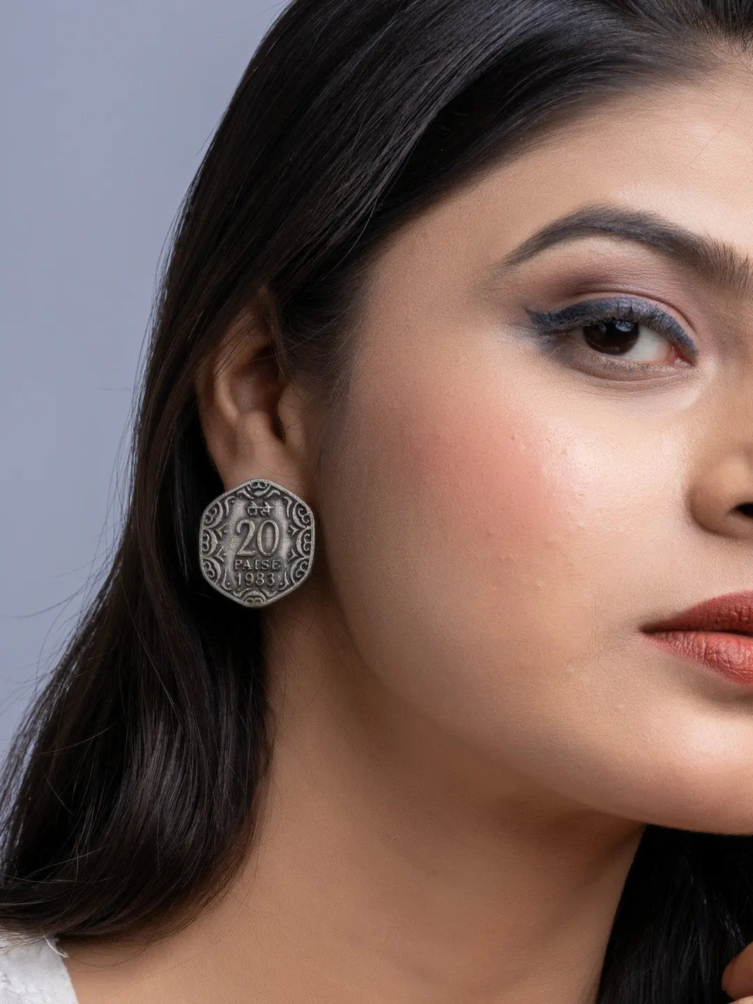 Close-up of oxidised silver earrings worn by a woman with long dark hair and makeup