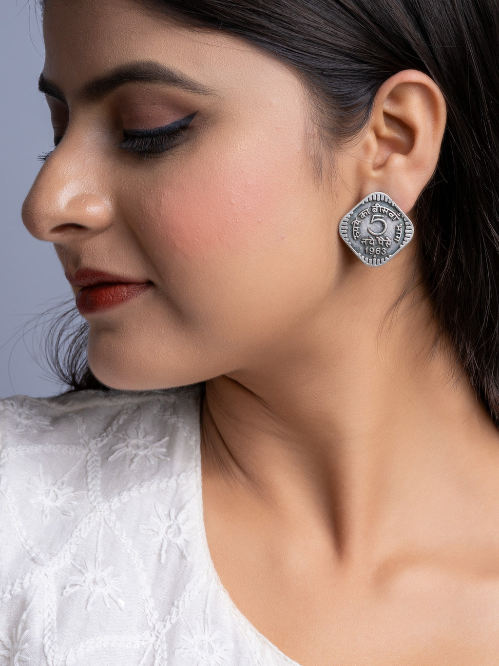 Close-up of a woman wearing oxidised silver earrings from LOOK AND ADORN with intricate coin design