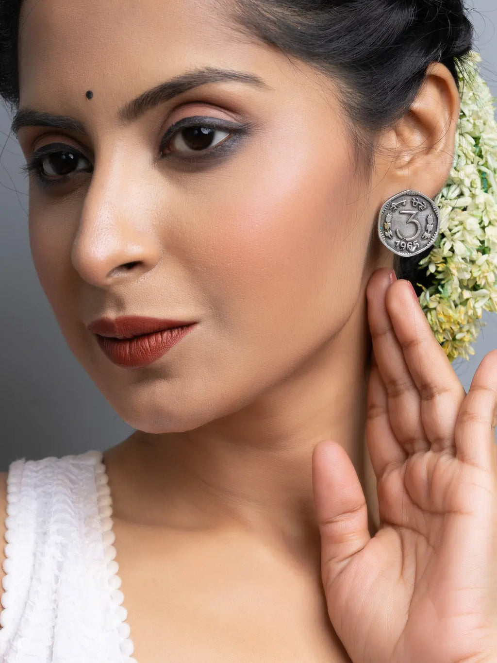 Close-up of a woman wearing oxidised silver earrings from LOOK AND ADORN with floral hair accessories
