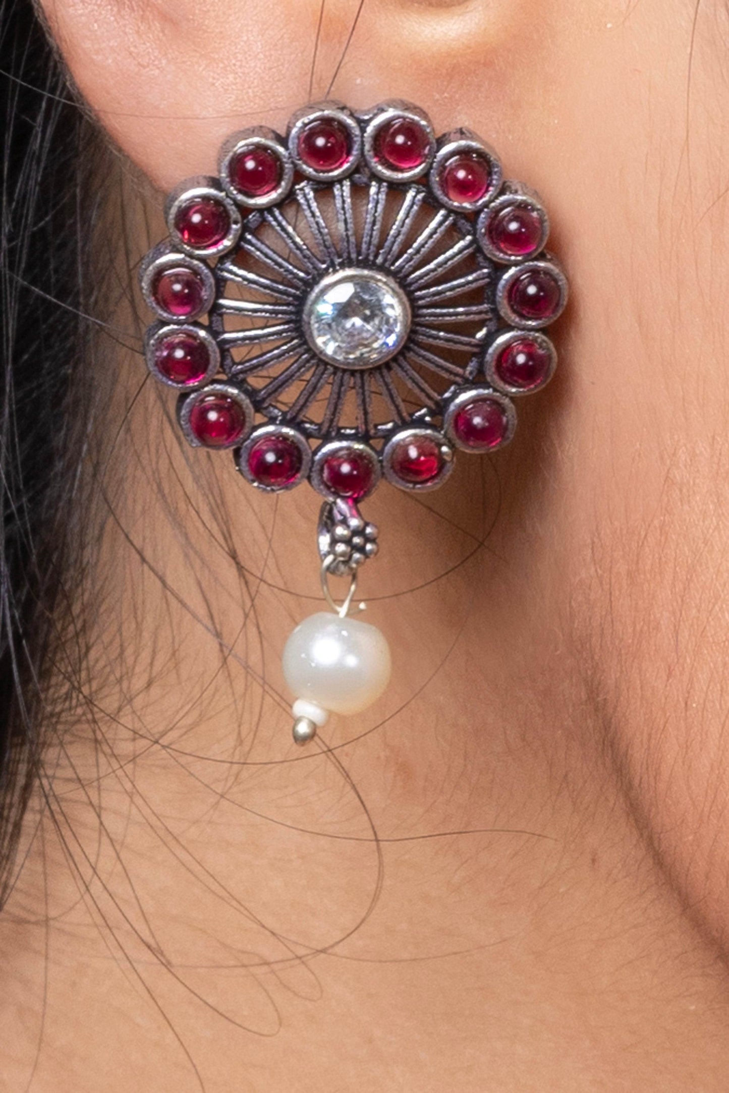 Oxidised silver stud earring with red stones and a pearl hanging design for a stylish look