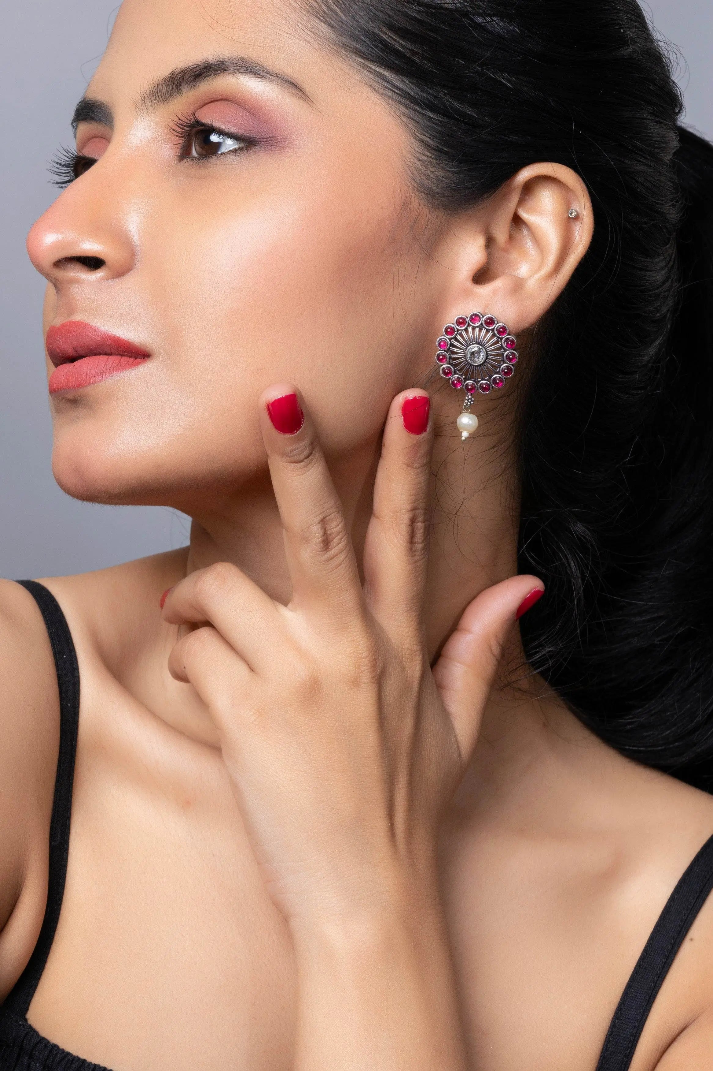 Oxidised silver stud earring with intricate design and colorful accents, modeled by a woman