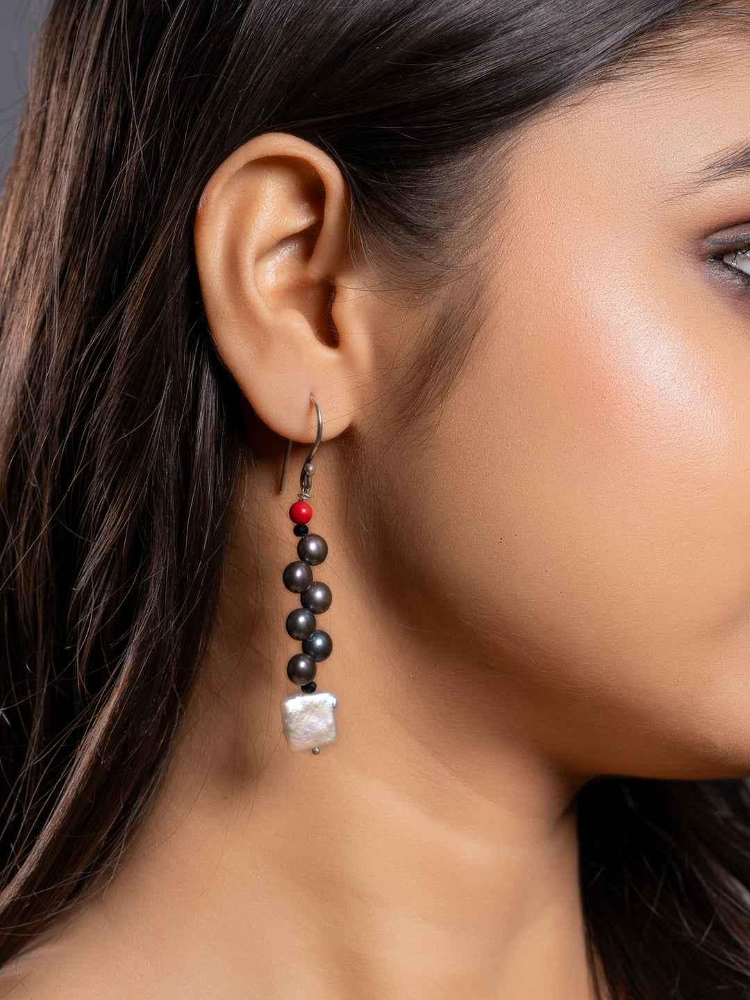 Elegant pearl earrings featuring black beads and a striking red accent in a contemporary design