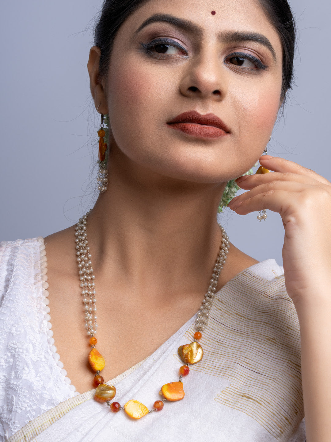 Elegant handmade mother of pearl necklace set with orange and pearl beads worn by woman