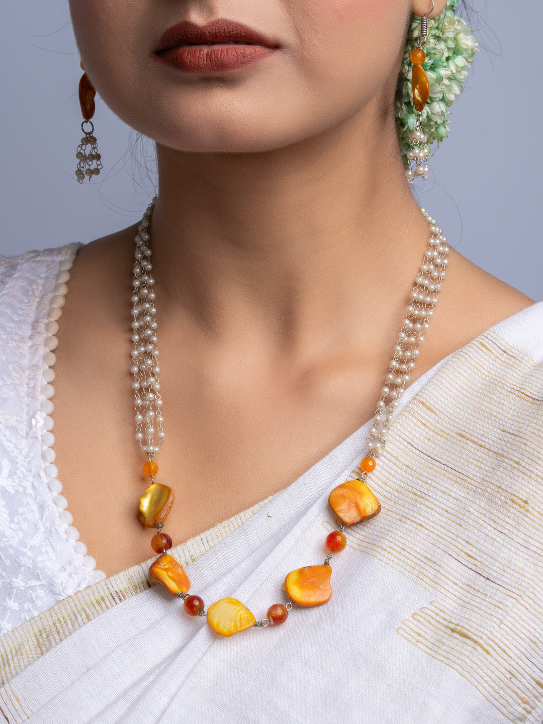 Handmade mother of pearl necklace set with amber stones worn with traditional white saree and earrings