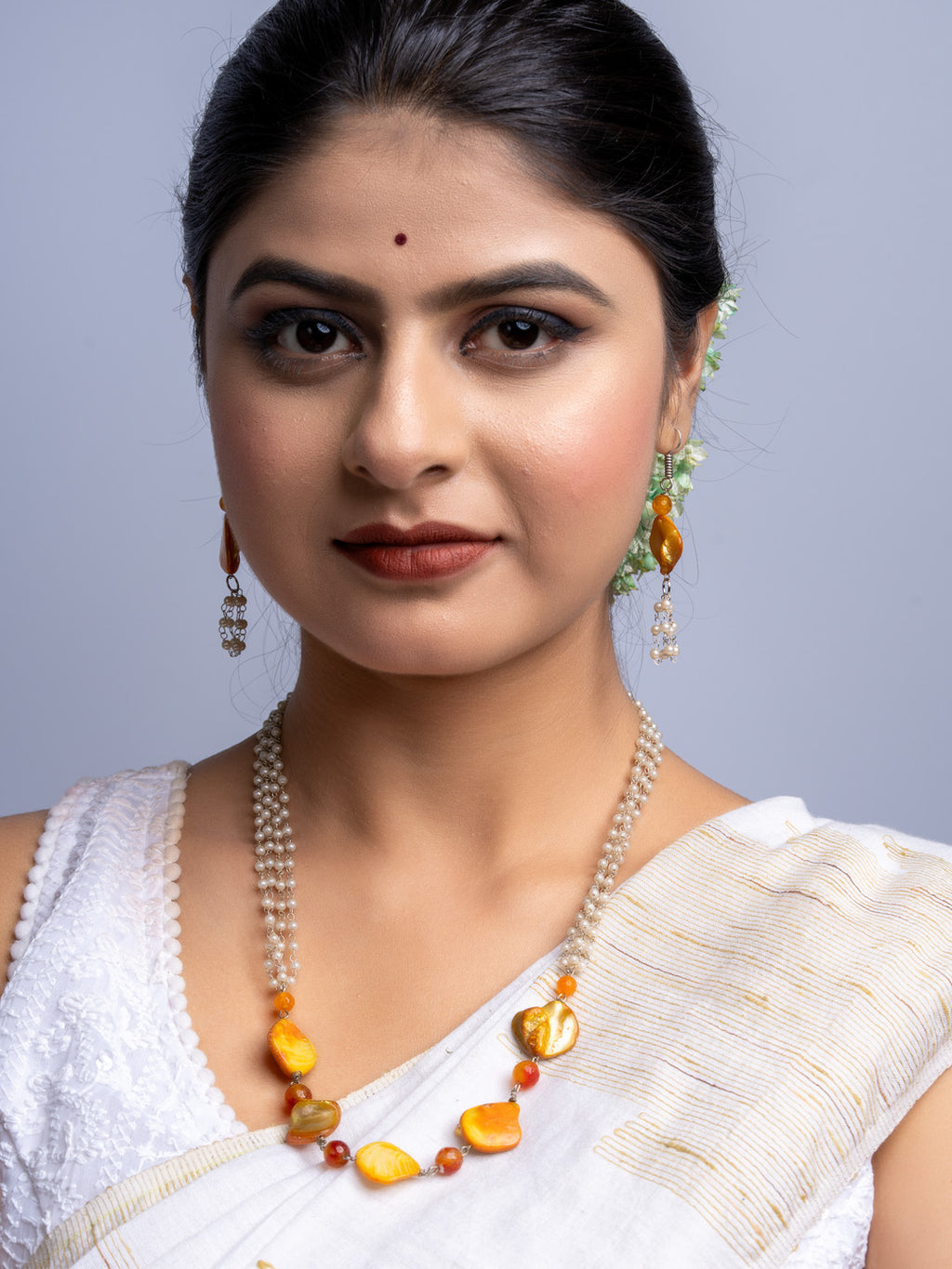 Woman wearing handmade mother of pearl necklace set with orange and cream beads by LOOK AND ADORN