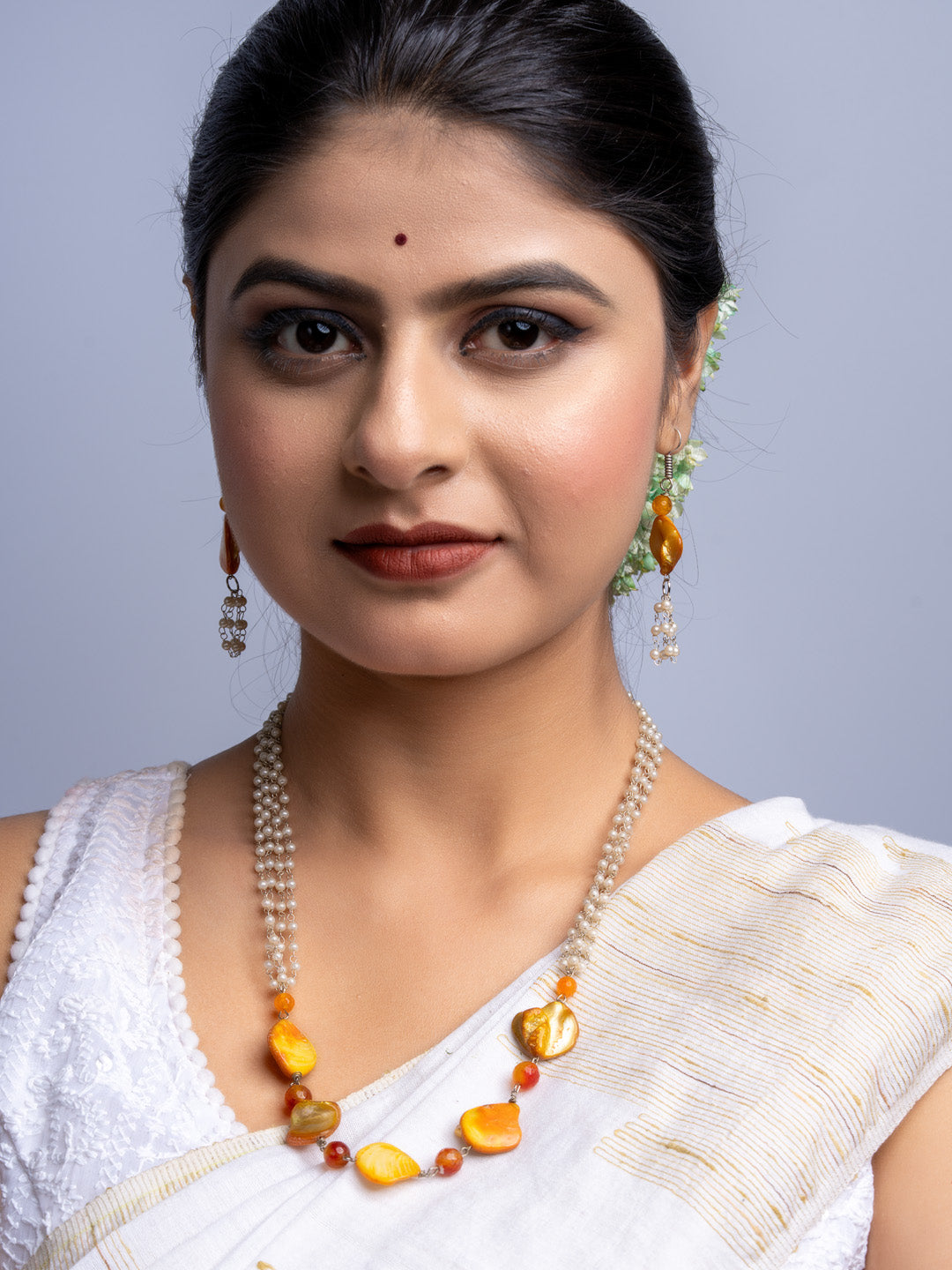 Woman wearing handmade mother of pearl necklace set with orange and cream beads by LOOK AND ADORN