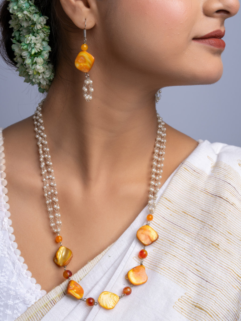 Handmade mother of pearl necklace set featuring orange and white beads worn with traditional attire