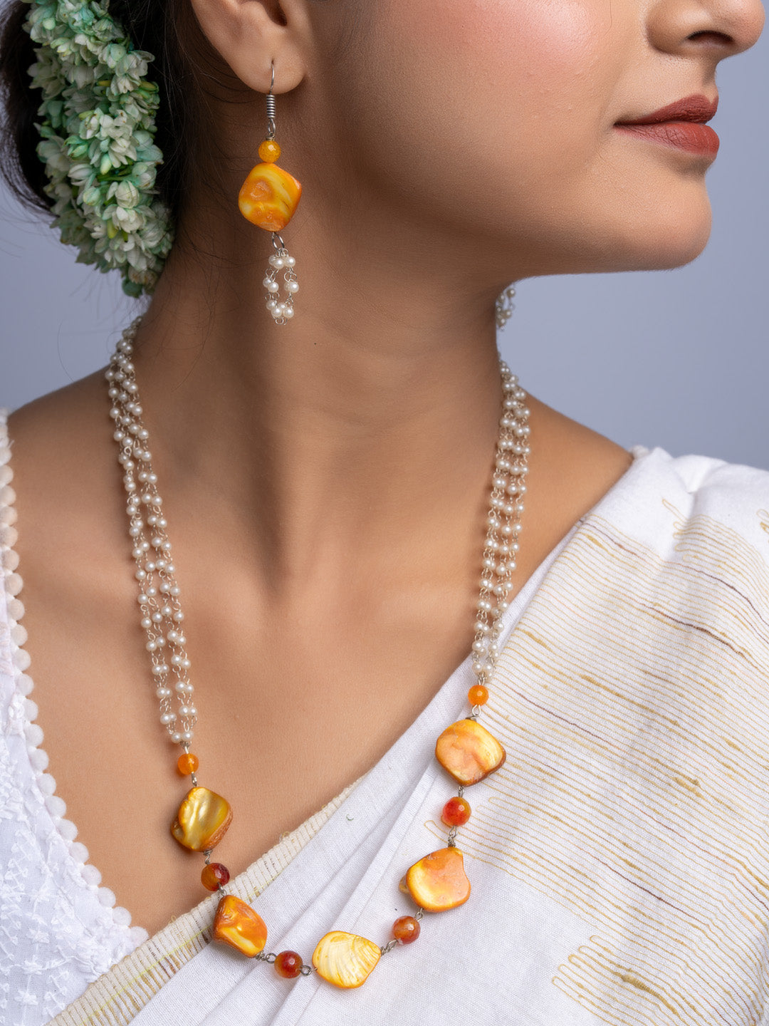 Handmade mother of pearl necklace set featuring orange and white beads worn with traditional attire