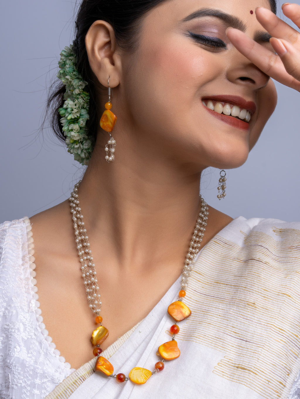 Elegant handmade mother of pearl necklace set featuring orange and pearl beads worn with traditional attire