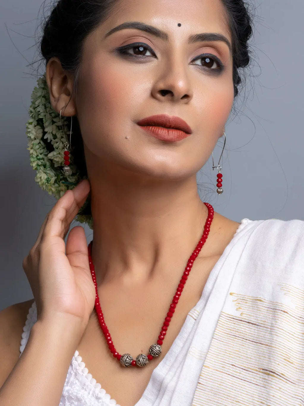 Red Crystal Necklace Set with silver beads worn by woman styled with matching earrings and traditional attire