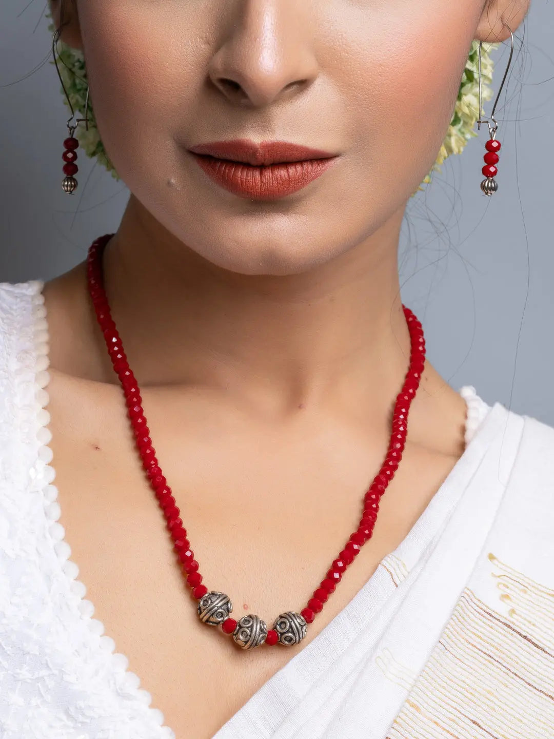 Close-up of woman wearing handmade Red Crystal Necklace Set with silver beads and matching earrings