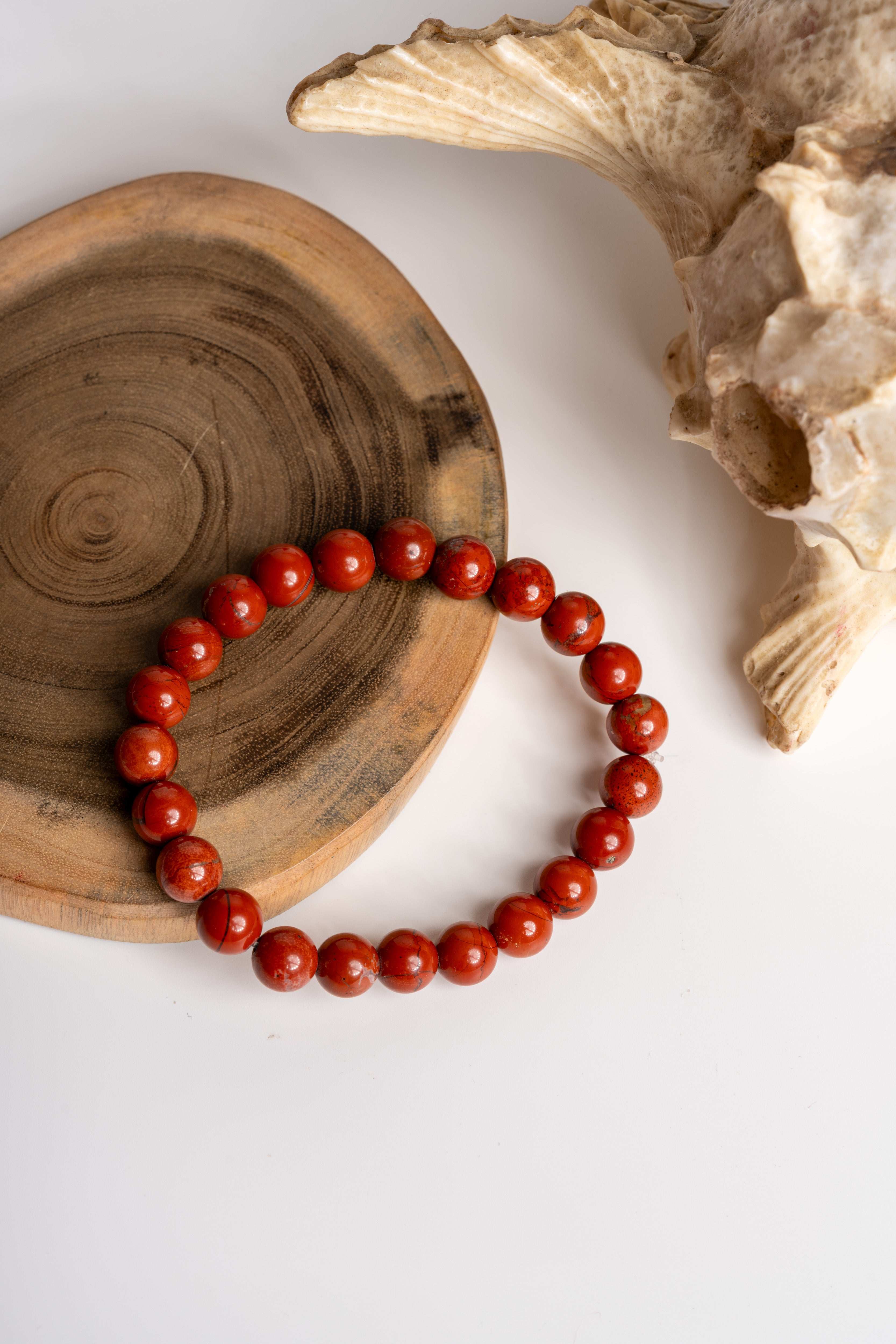 LOOK AND ADORN red jasper bracelet on a wooden surface with natural textures