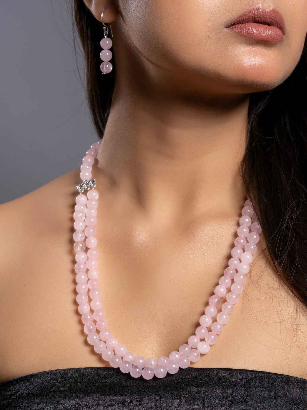 Rose quartz necklace set featuring multiple strands of soft pink beads, styled elegantly with matching earrings
