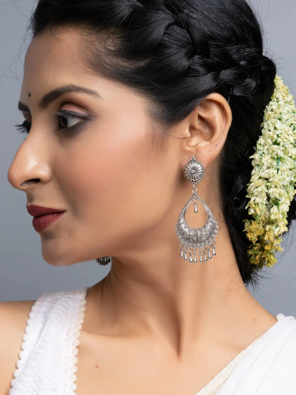 Oxidised silver chandbali earrings worn by woman with braided hair and white outfit
