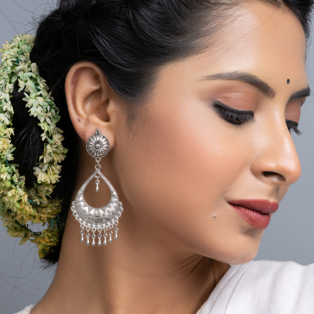 Oxidised silver chandbali earrings worn by a woman with braided hair and floral accessories