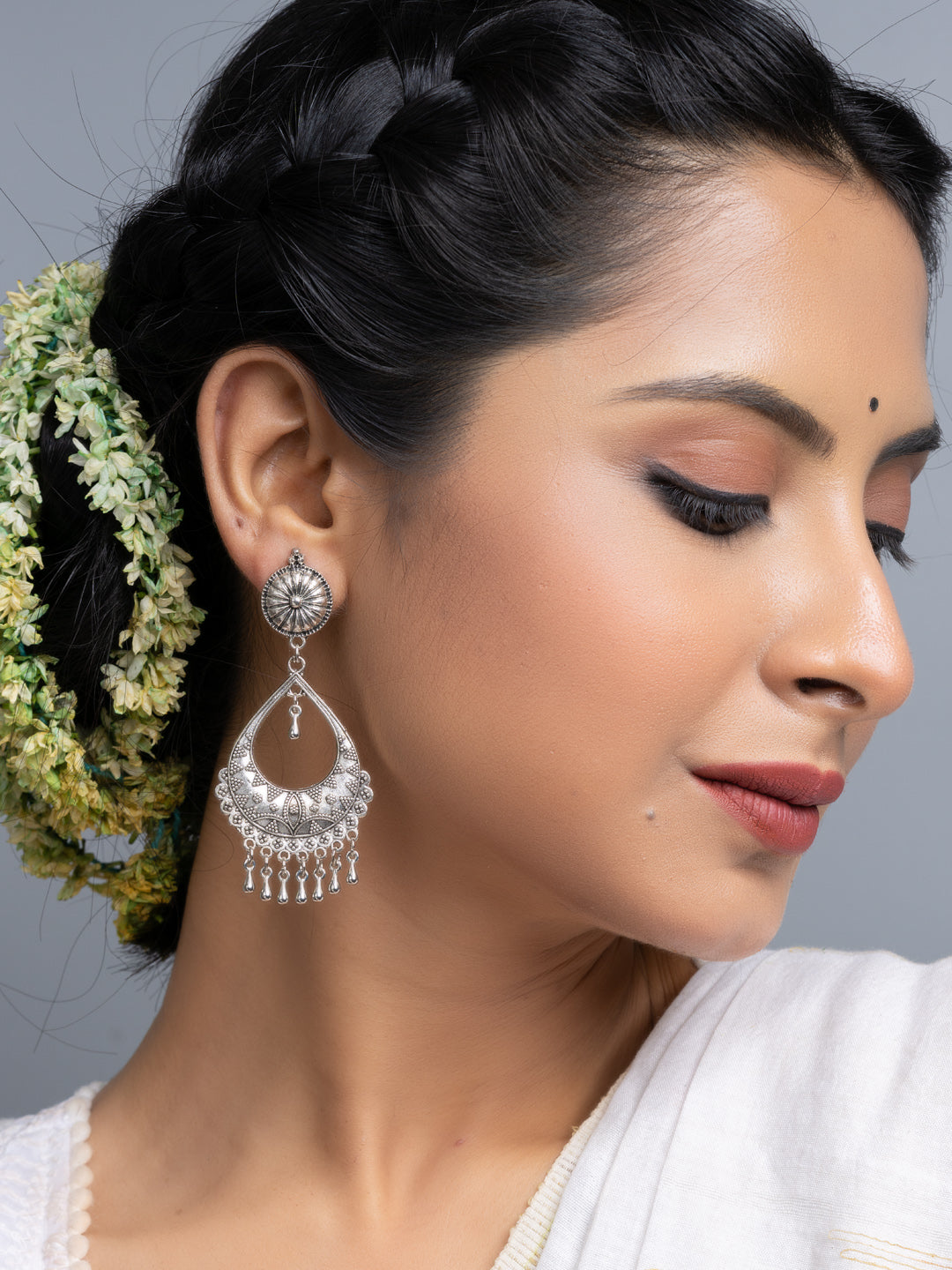 Oxidised silver chandbali earrings worn by a woman with braided hair and floral accessories