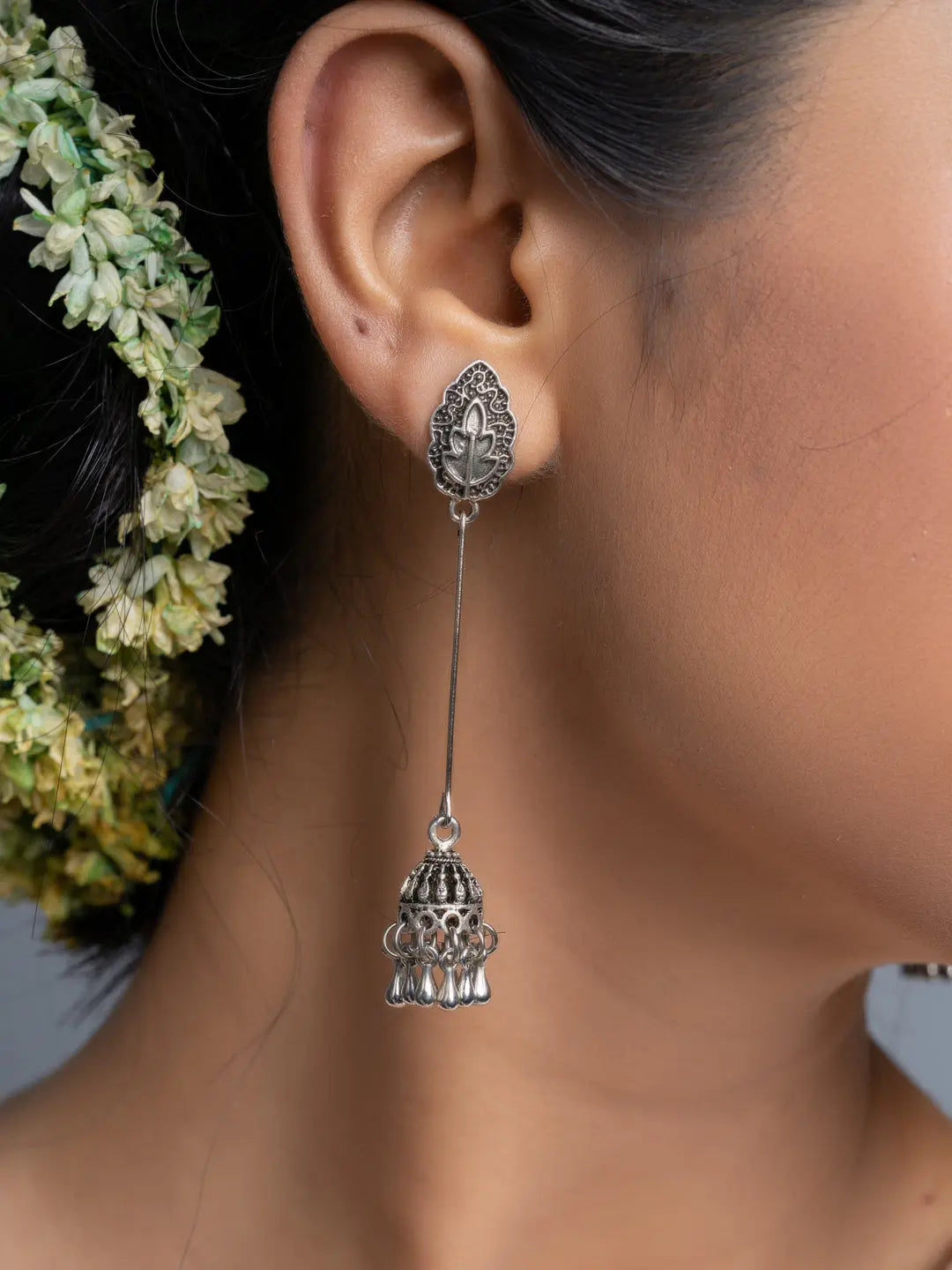 Close-up of oxidised silver jhumka earrings worn with floral hair accessories
